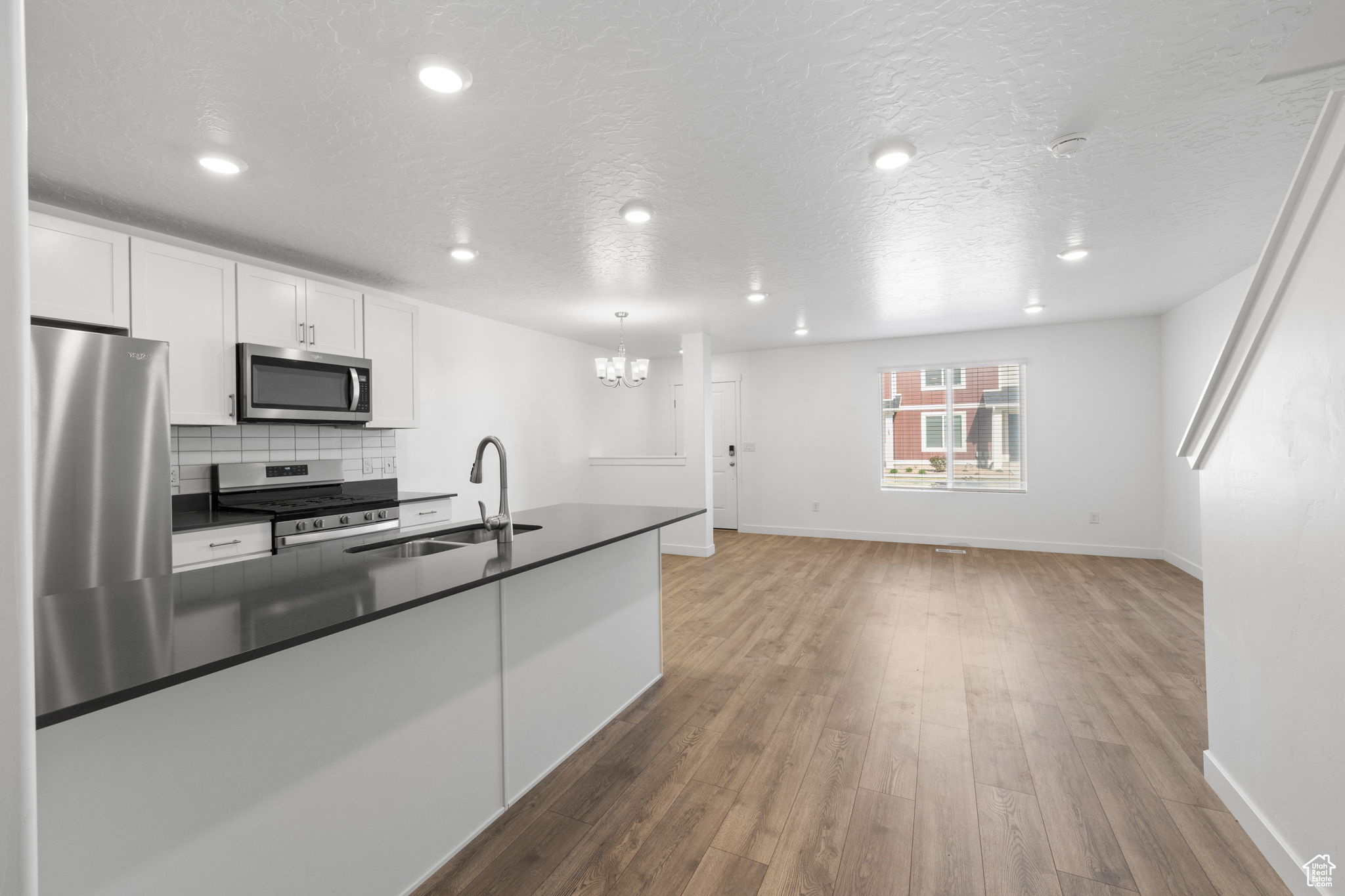 Kitchen featuring dark wood-type flooring, stainless steel appliances, white cabinets, and sink