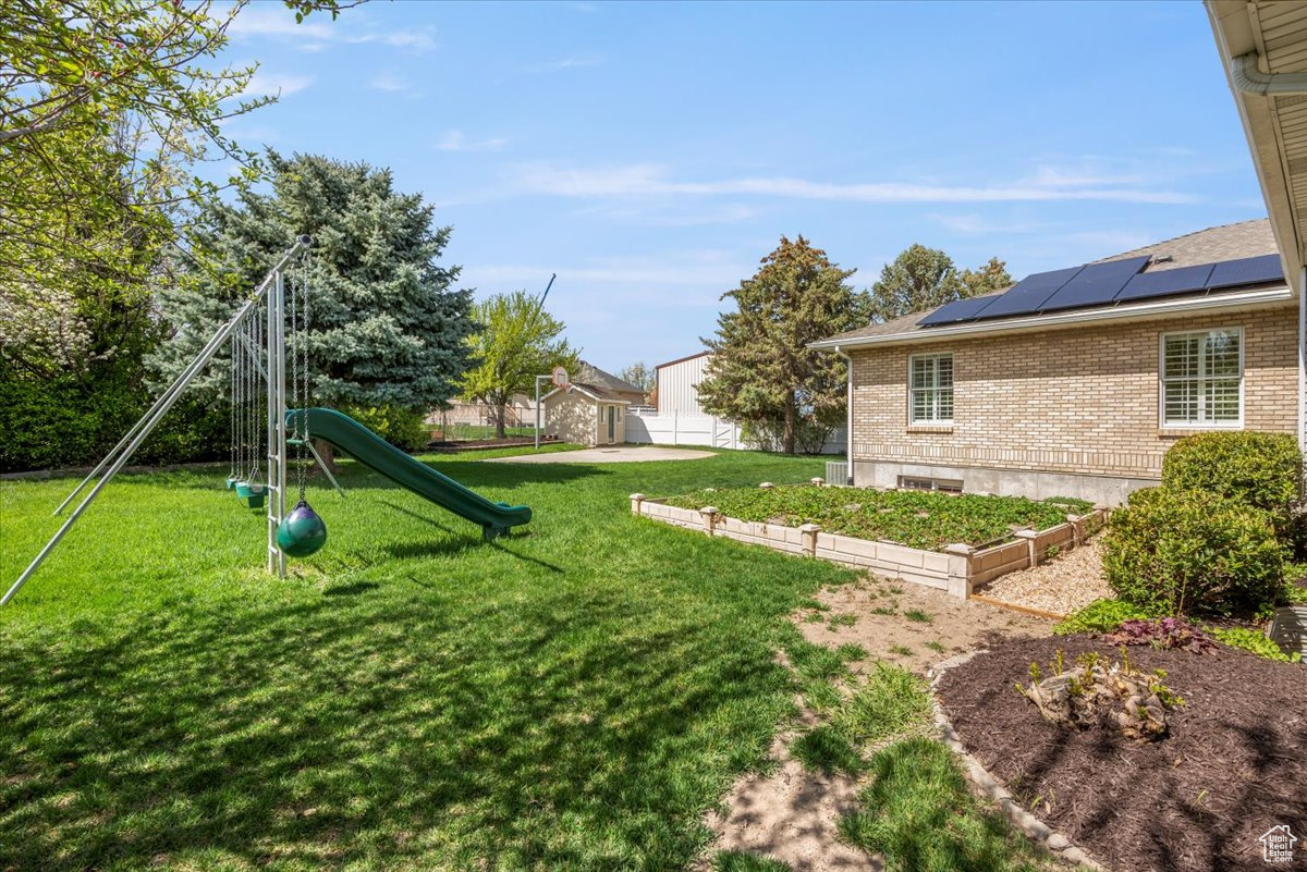 View of yard featuring a playground and strawberry beds