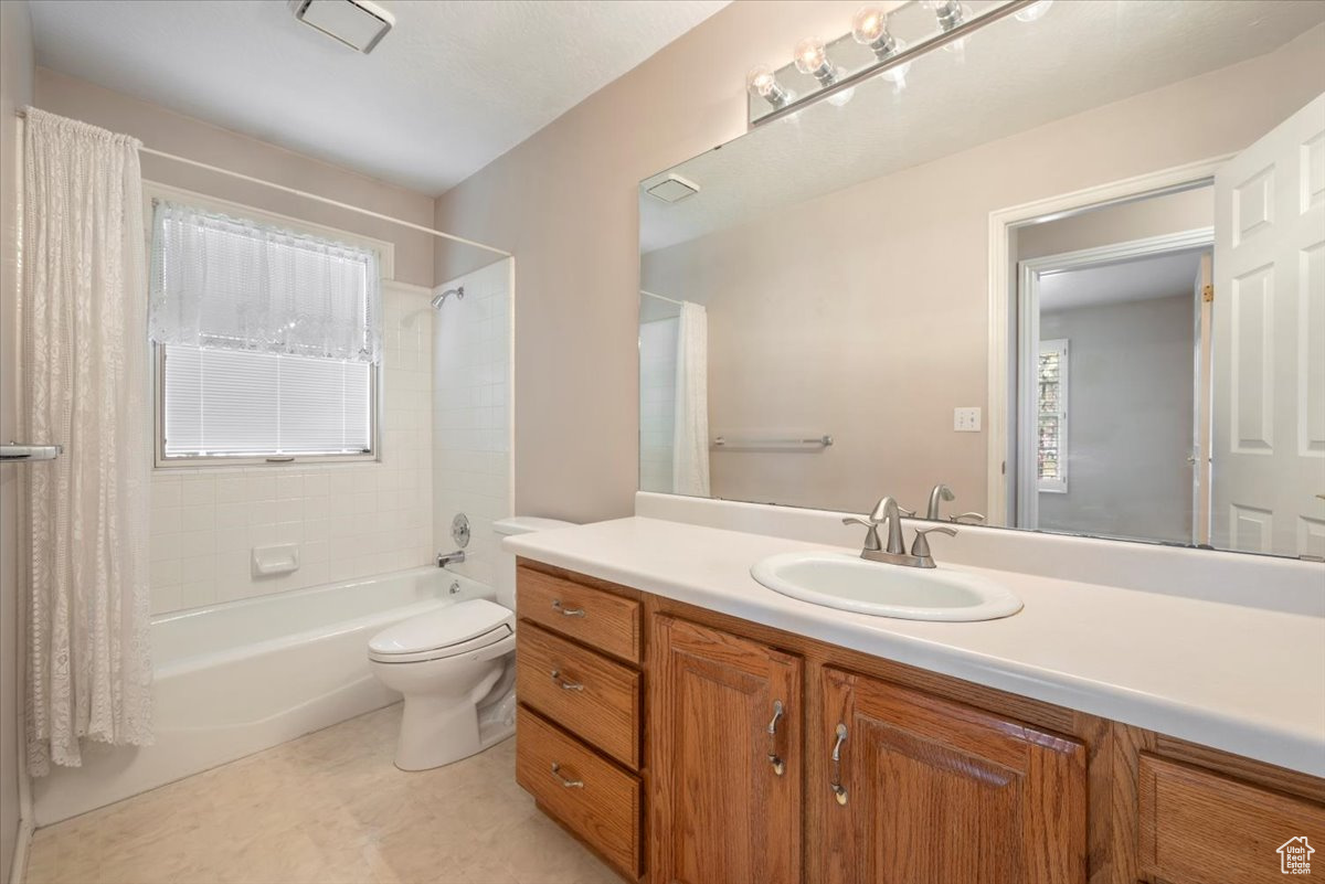 Full bathroom with a vanity, a wealth of natural light, shower / bath combination, and toilet