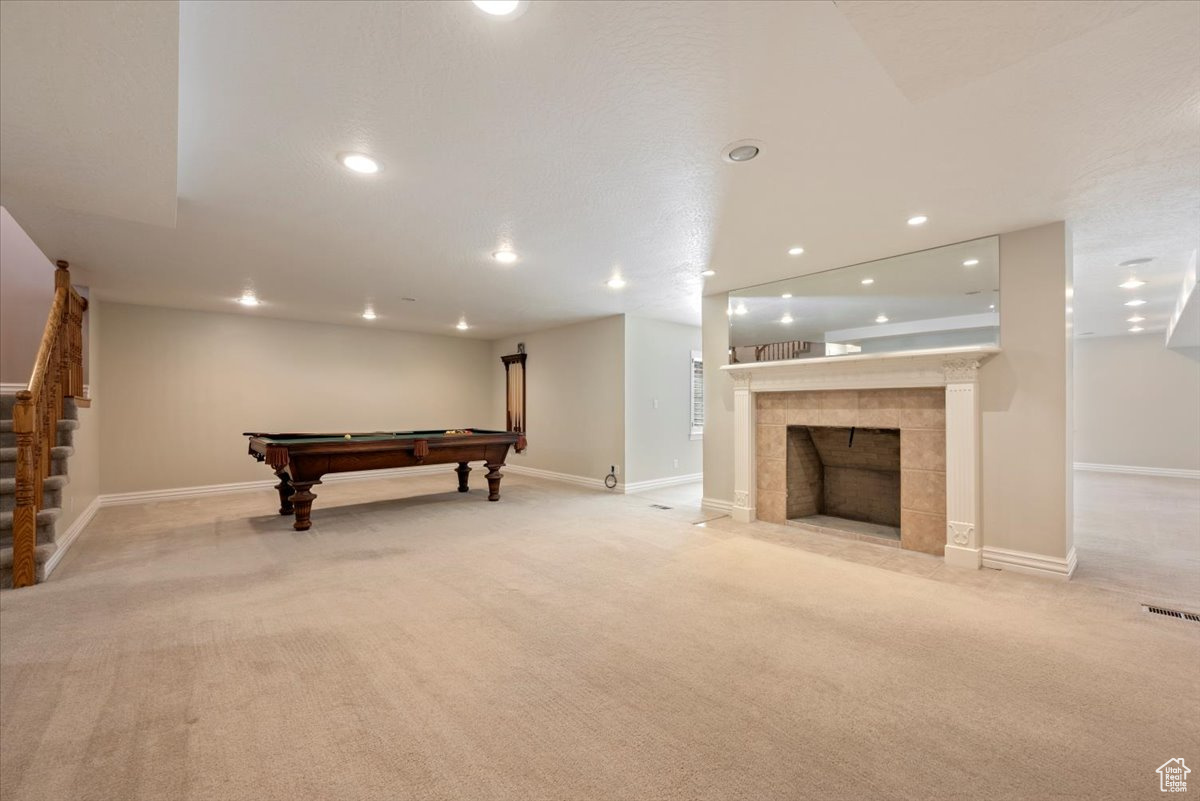Family room featuring light colored carpet, a tile fireplace, and pool table
