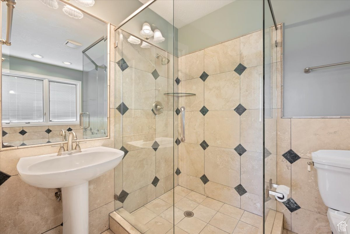 Primary bathroom featuring tiled shower, tile walls, tasteful backsplash, and toilet