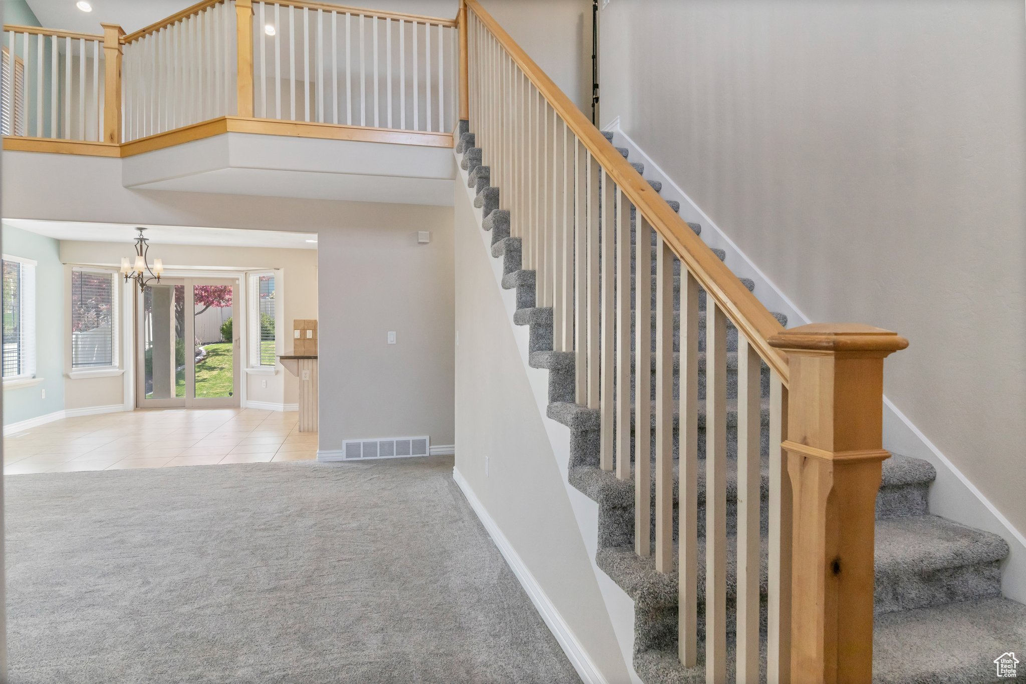 Stairs featuring light colored carpet, an inviting chandelier, and a high ceiling