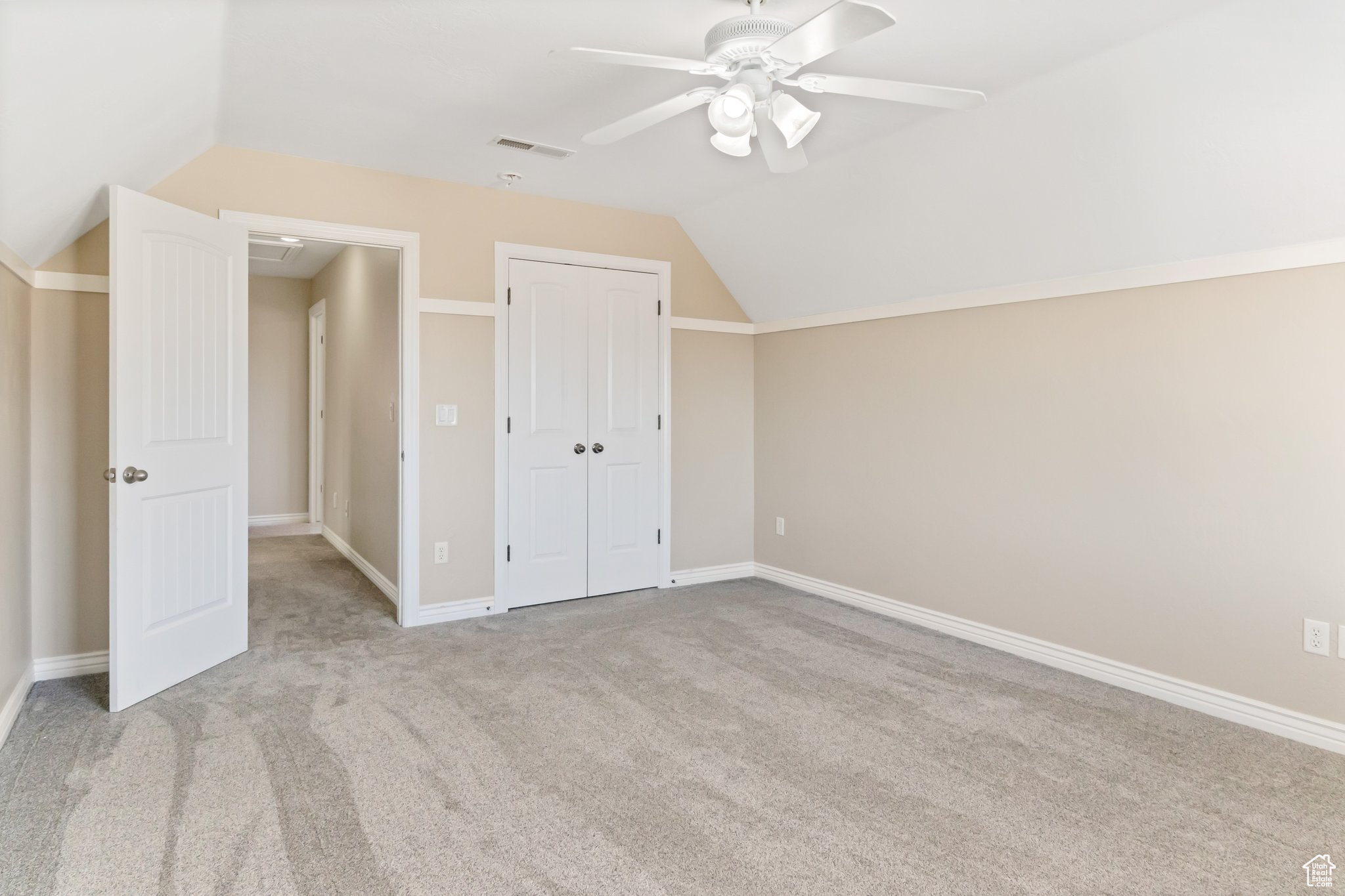 Additional living space featuring light colored carpet, lofted ceiling, and ceiling fan