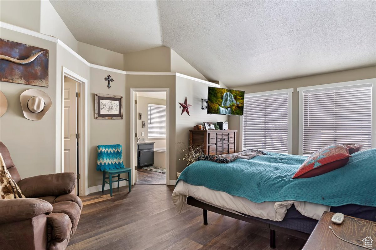 Bedroom with dark hardwood / wood-style flooring, ensuite bath, high vaulted ceiling, and a textured ceiling