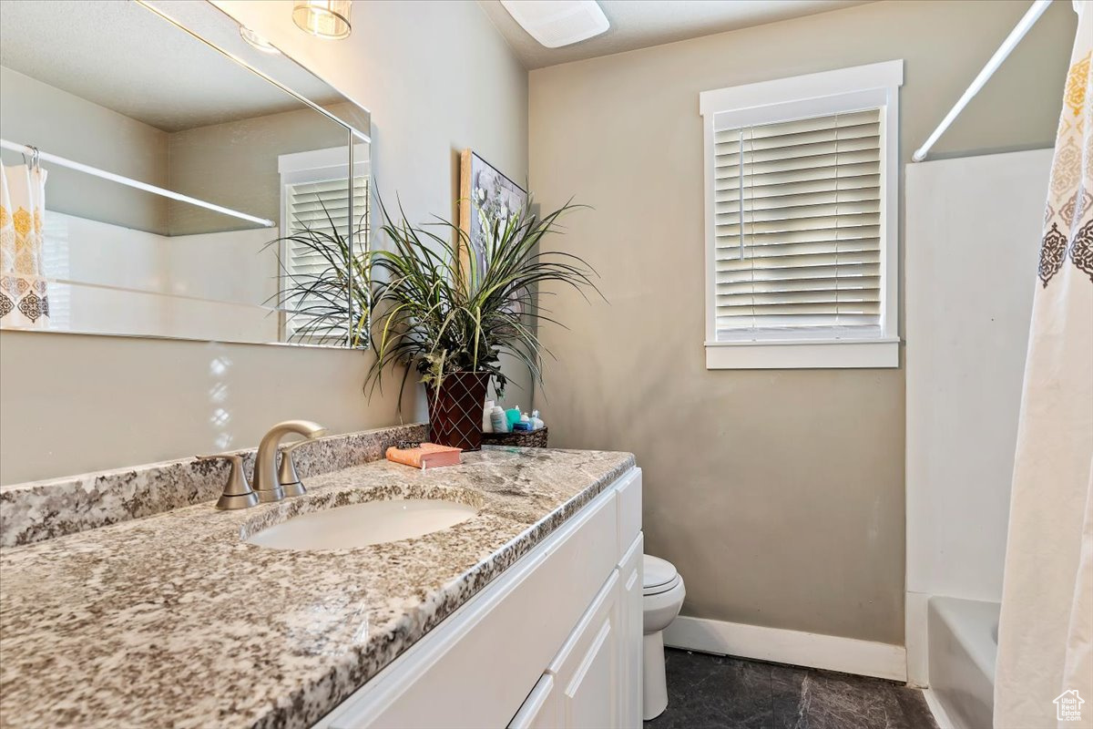 Full bathroom with shower / tub combo with curtain, toilet, vanity, and tile flooring