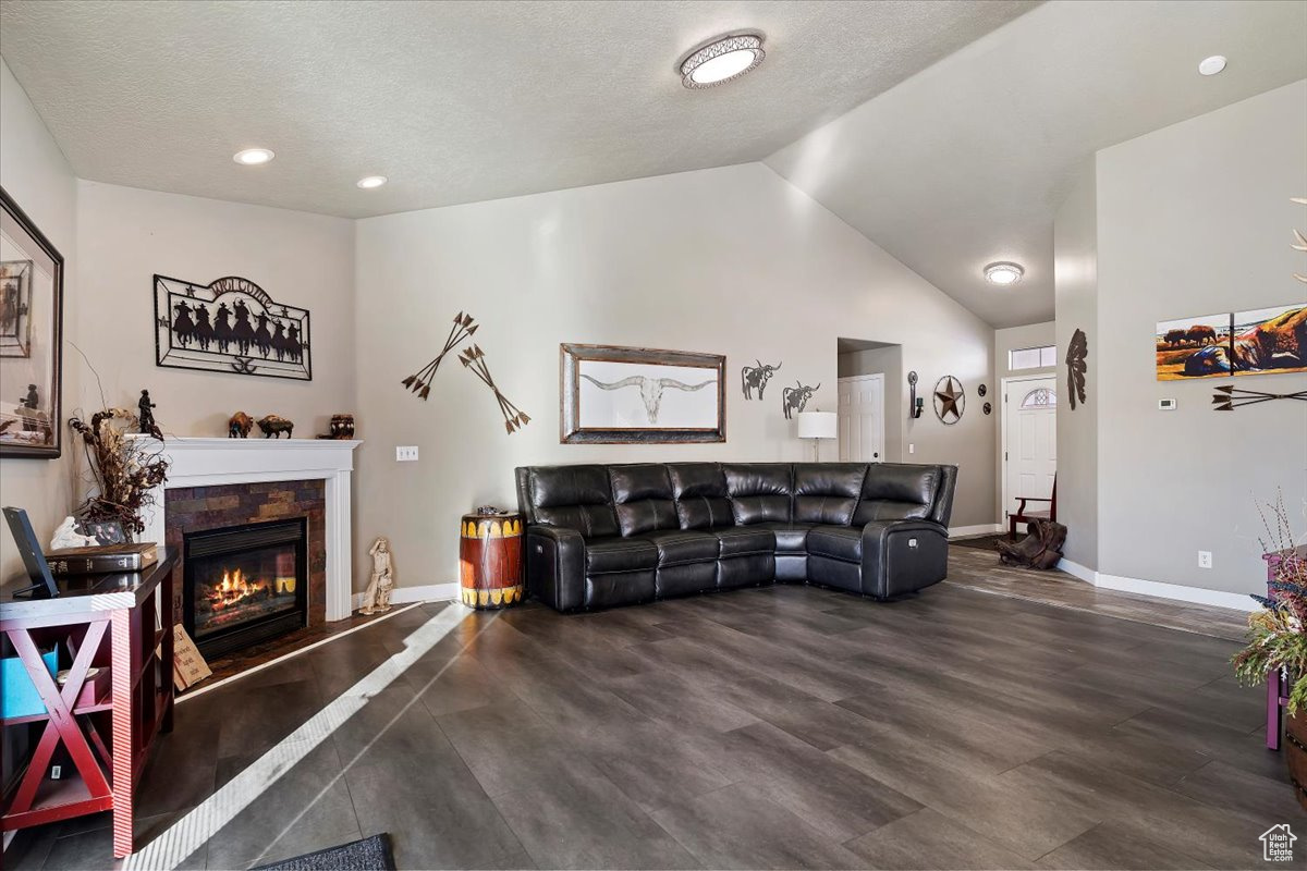 Living room featuring a textured ceiling, dark hardwood / wood-style floors, and lofted ceiling
