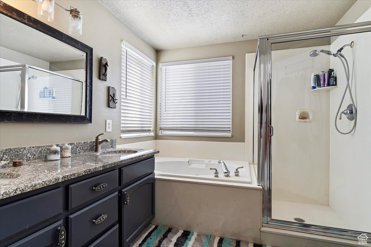 Bathroom with vanity with extensive cabinet space, plus walk in shower, and a textured ceiling