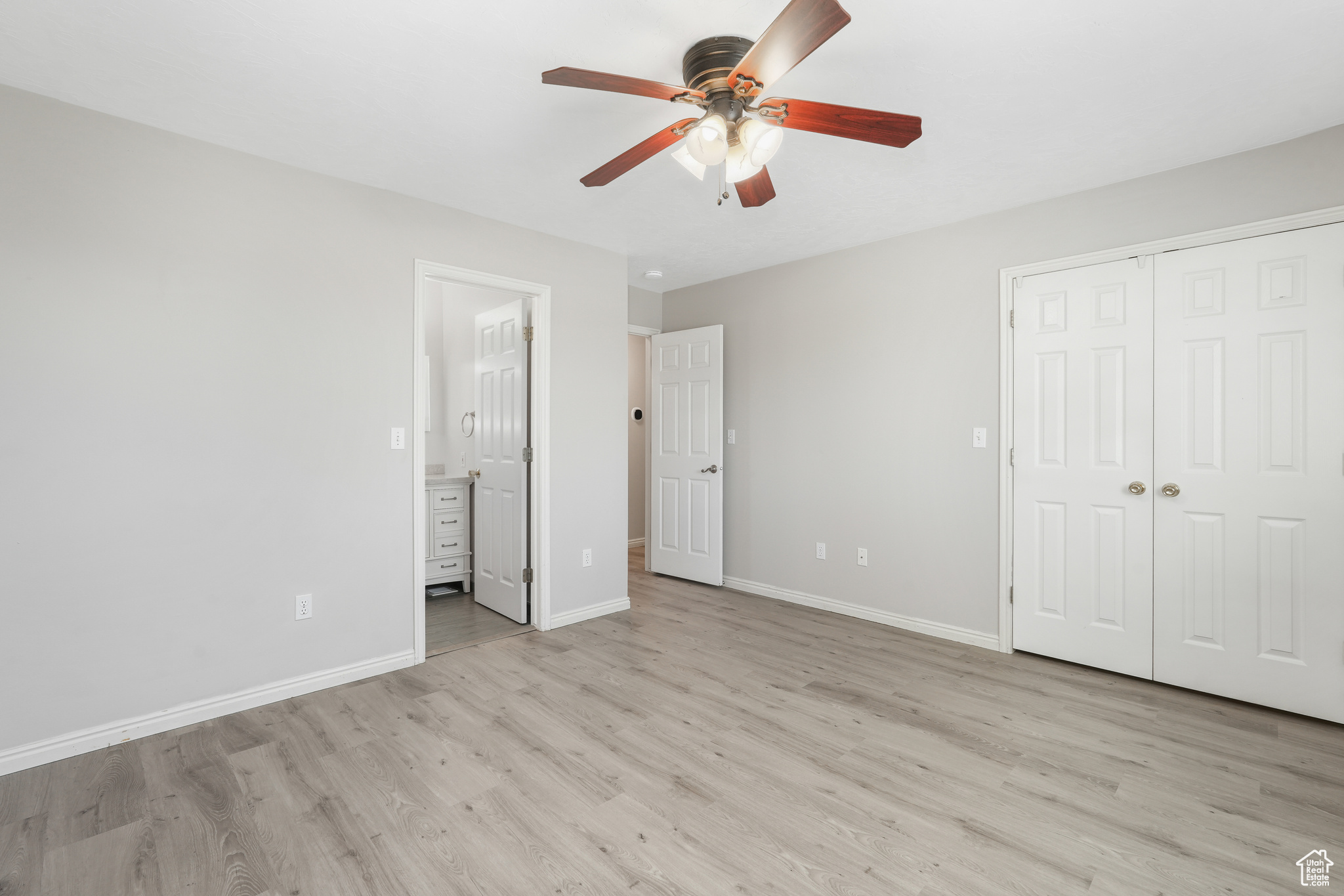 Primary bedroom featuring a closet, light hardwood / wood-style floors, ceiling fan, and ensuite bathroom