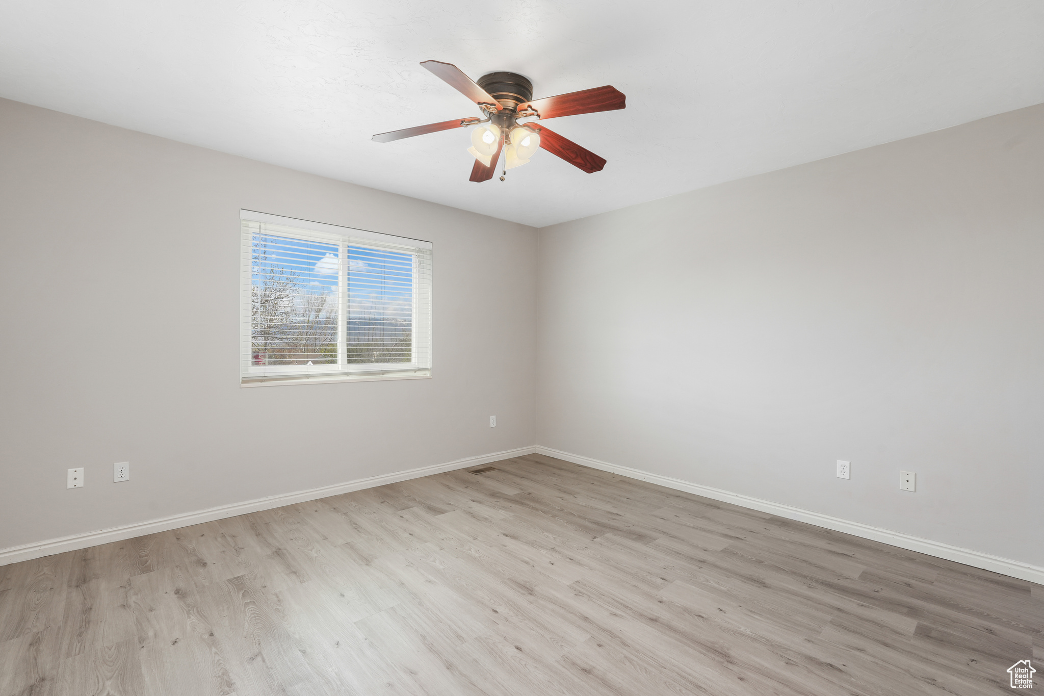 Unfurnished room with ceiling fan and light wood-type flooring