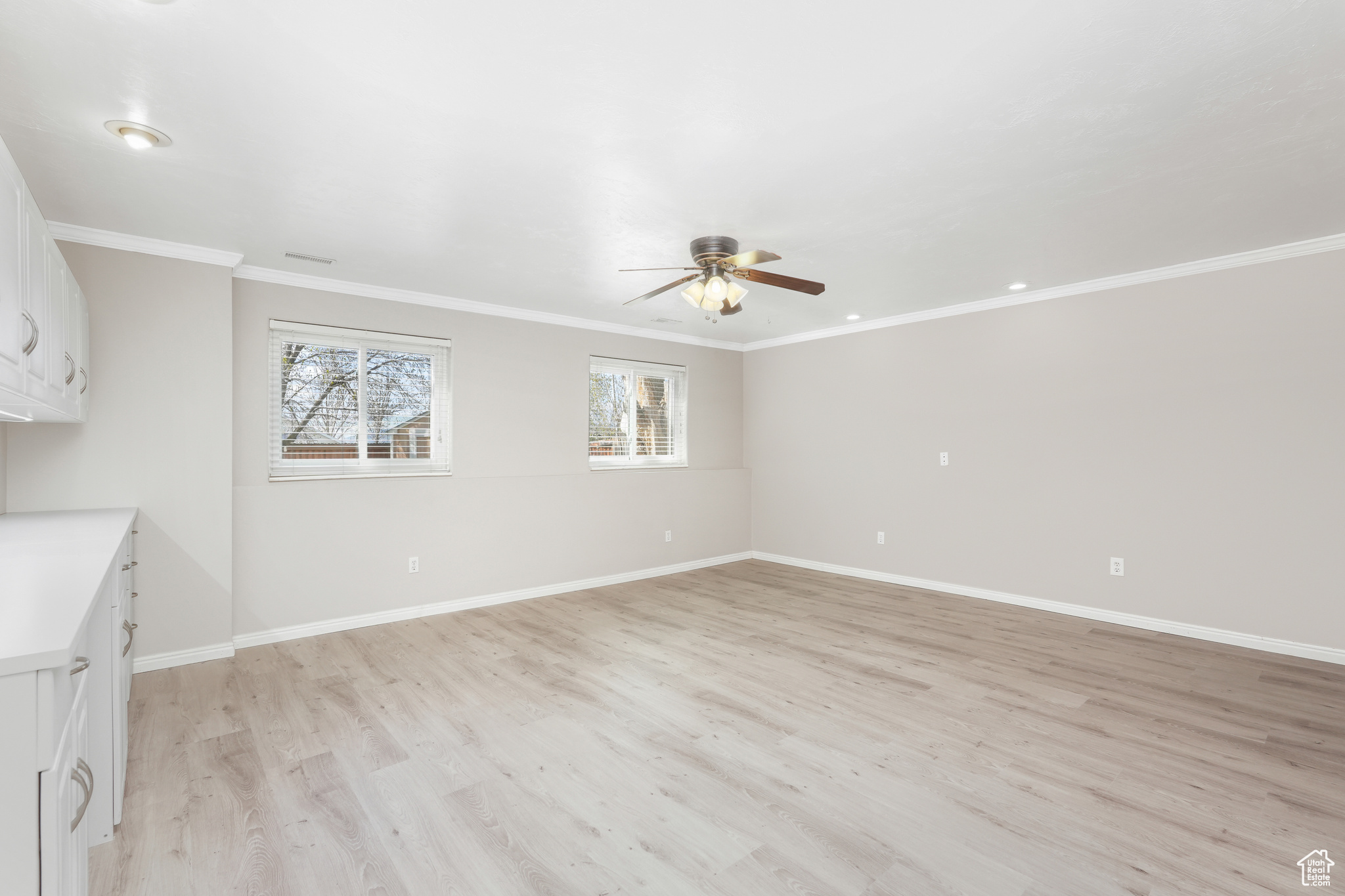 Unfurnished room featuring ornamental molding, ceiling fan, and light wood-type flooring