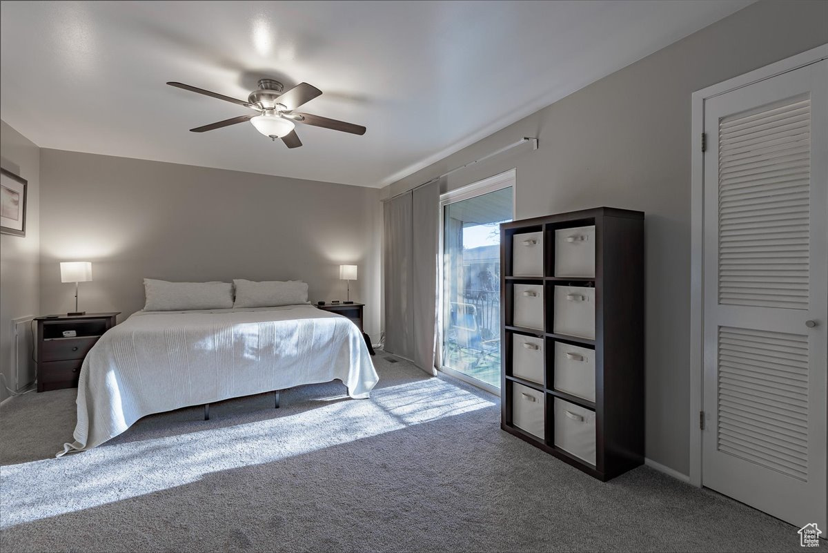 Carpeted bedroom with a closet, ceiling fan, and access to exterior