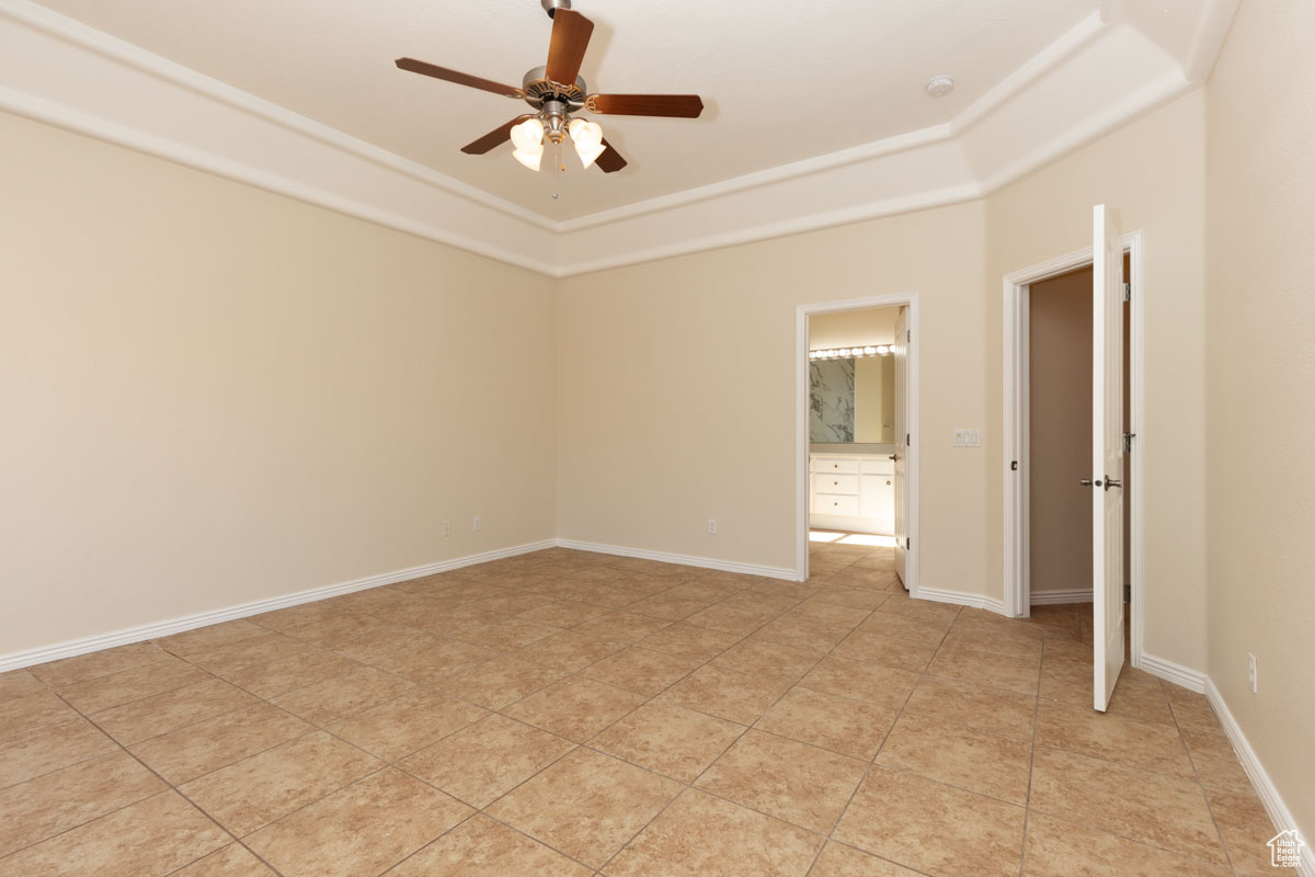 Tiled spare room featuring ceiling fan and a tray ceiling. this is the Primary bedroom with a sliding glass door leading to the back yard.