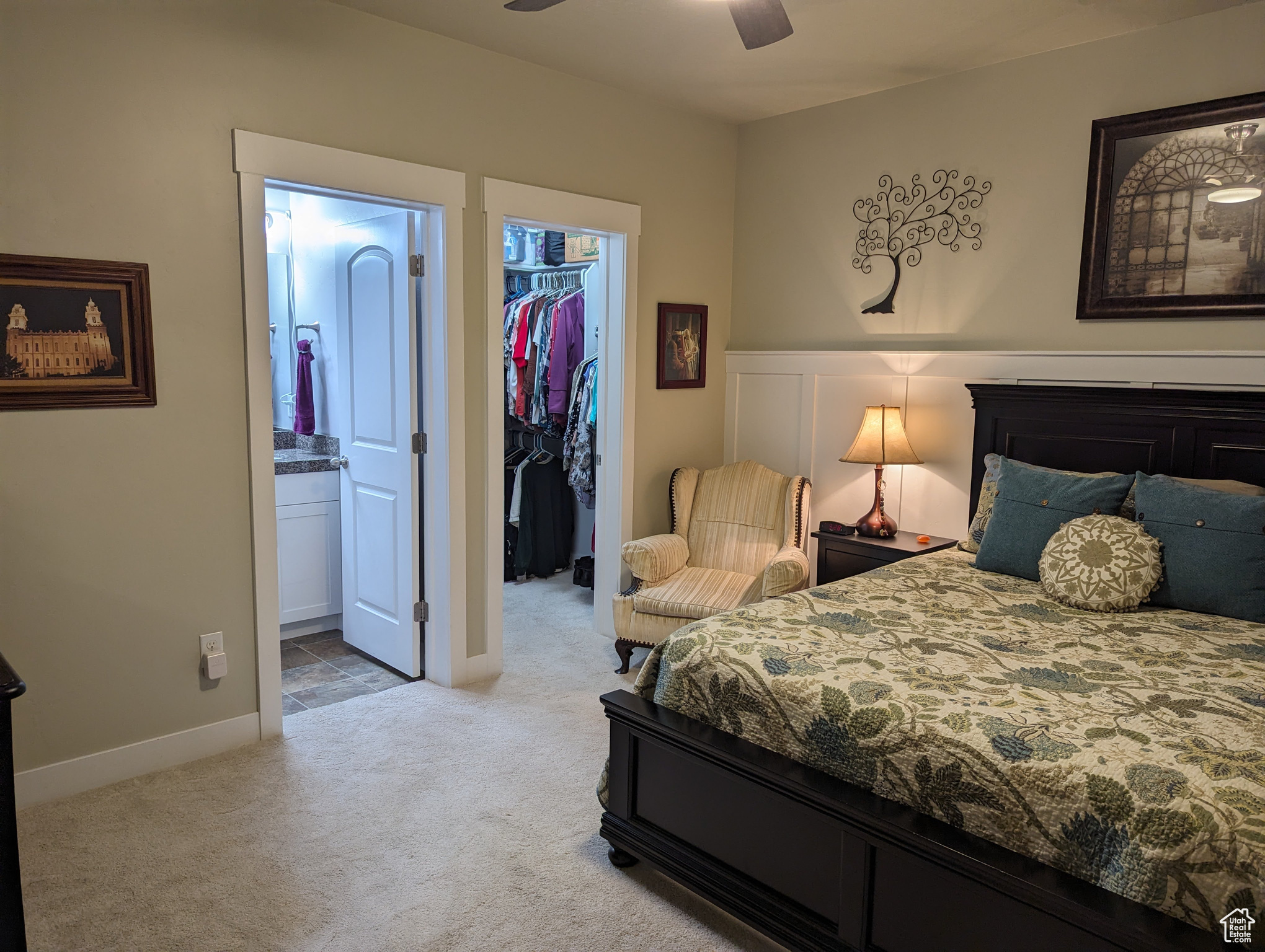 Bedroom with light colored carpet, a spacious closet, ensuite bath, ceiling fan, and a closet
