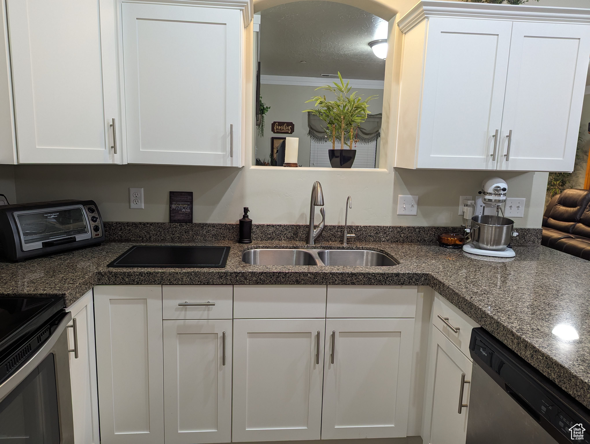 Kitchen featuring sink, white cabinetry, dishwasher, and ornamental molding