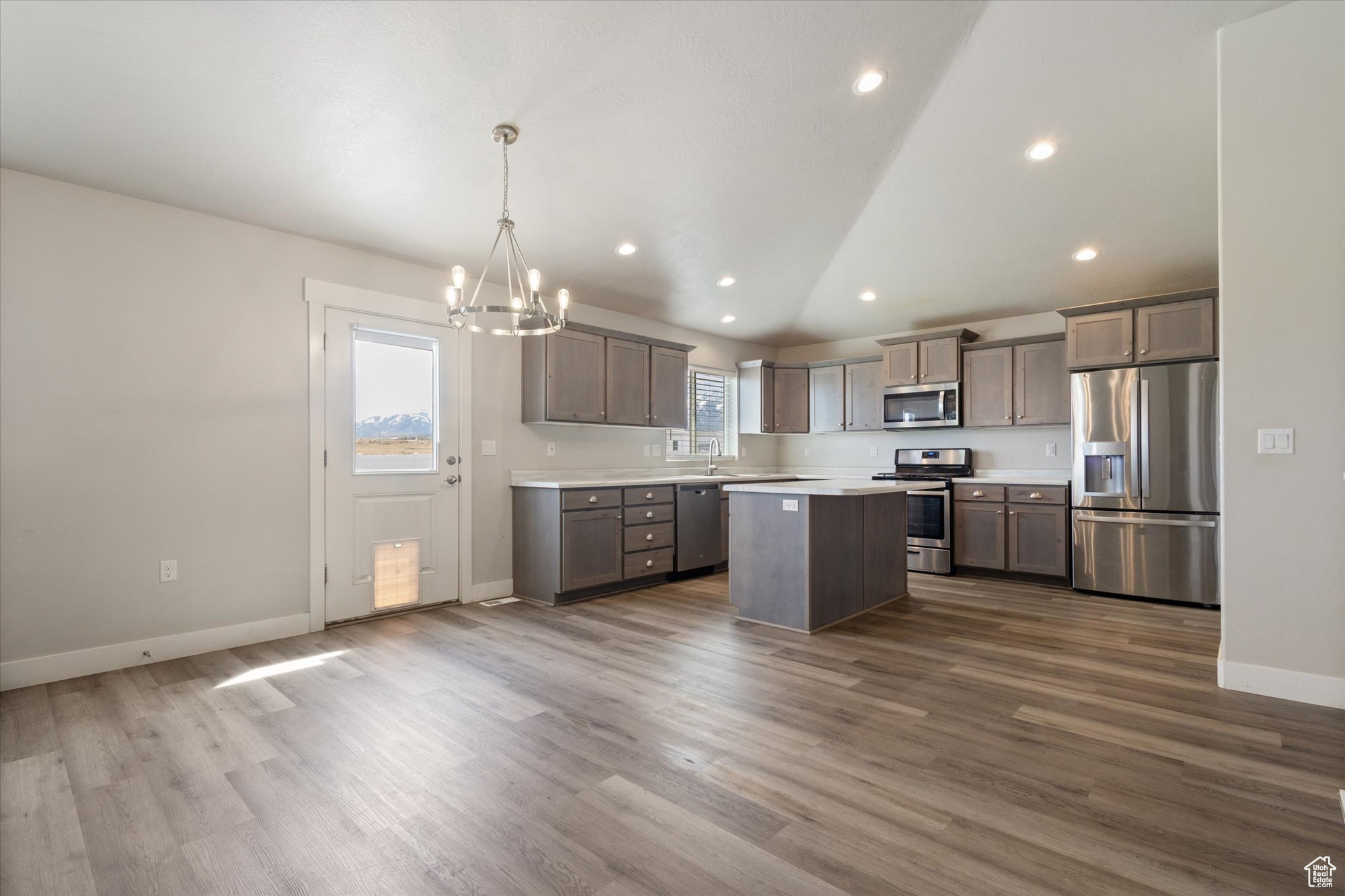 Kitchen featuring hanging light fixtures, dark hardwood / wood-style floors, stainless steel appliances, and a center island