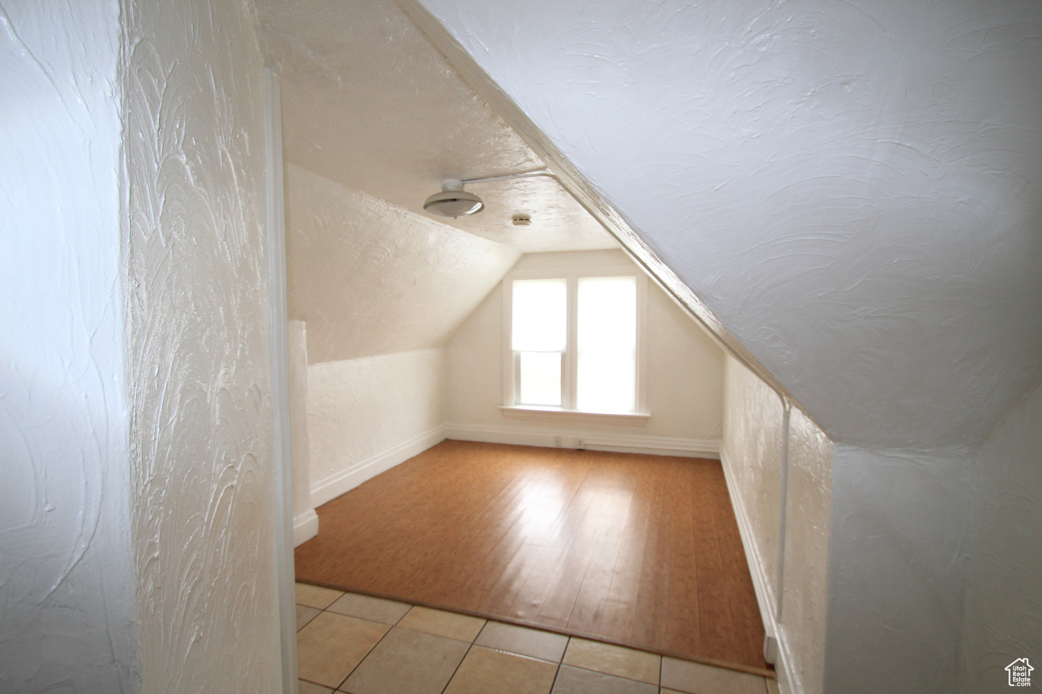 Bonus room with vaulted ceiling and light tile flooring