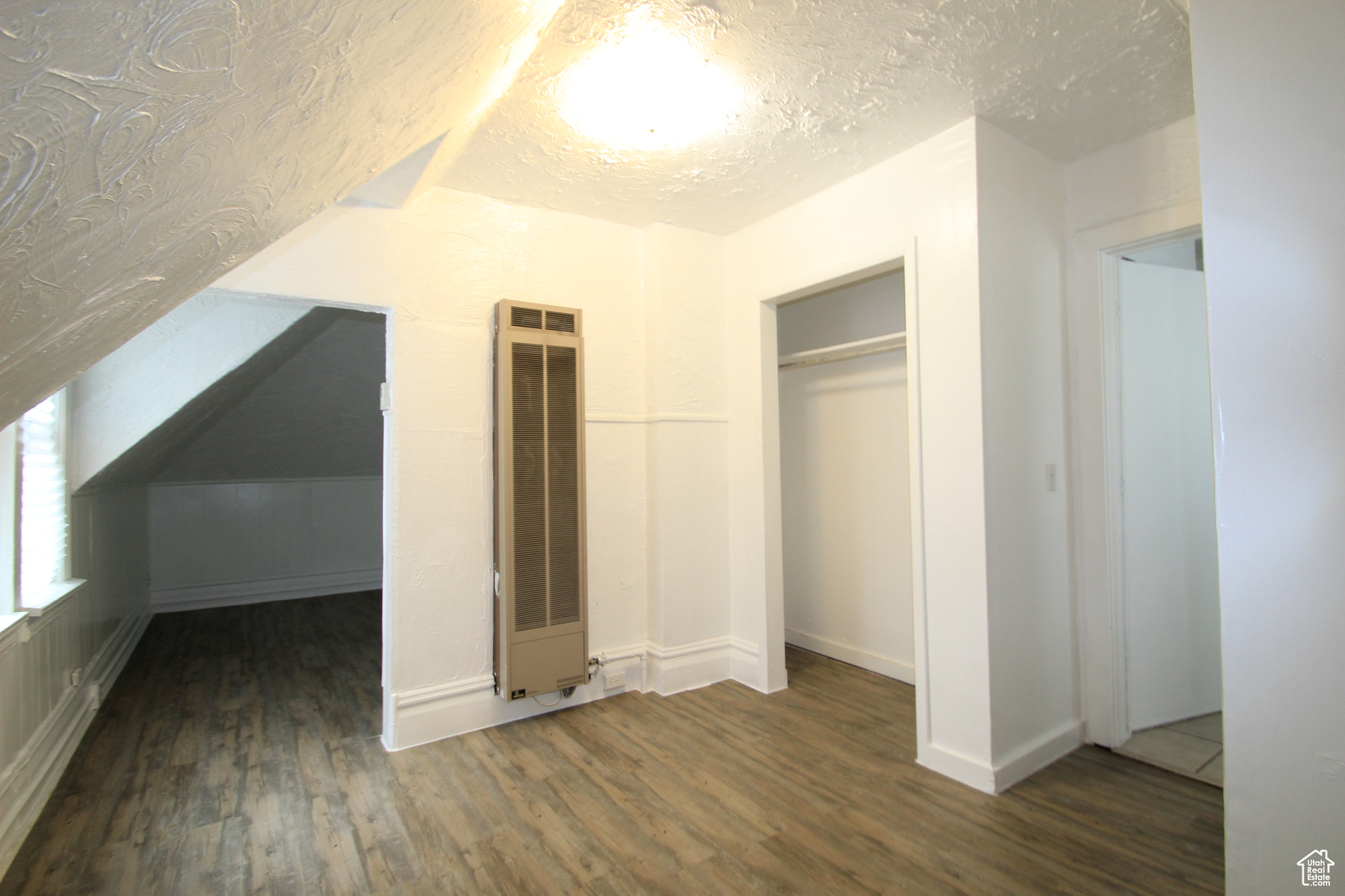 Bonus room with dark hardwood / wood-style flooring and a textured ceiling