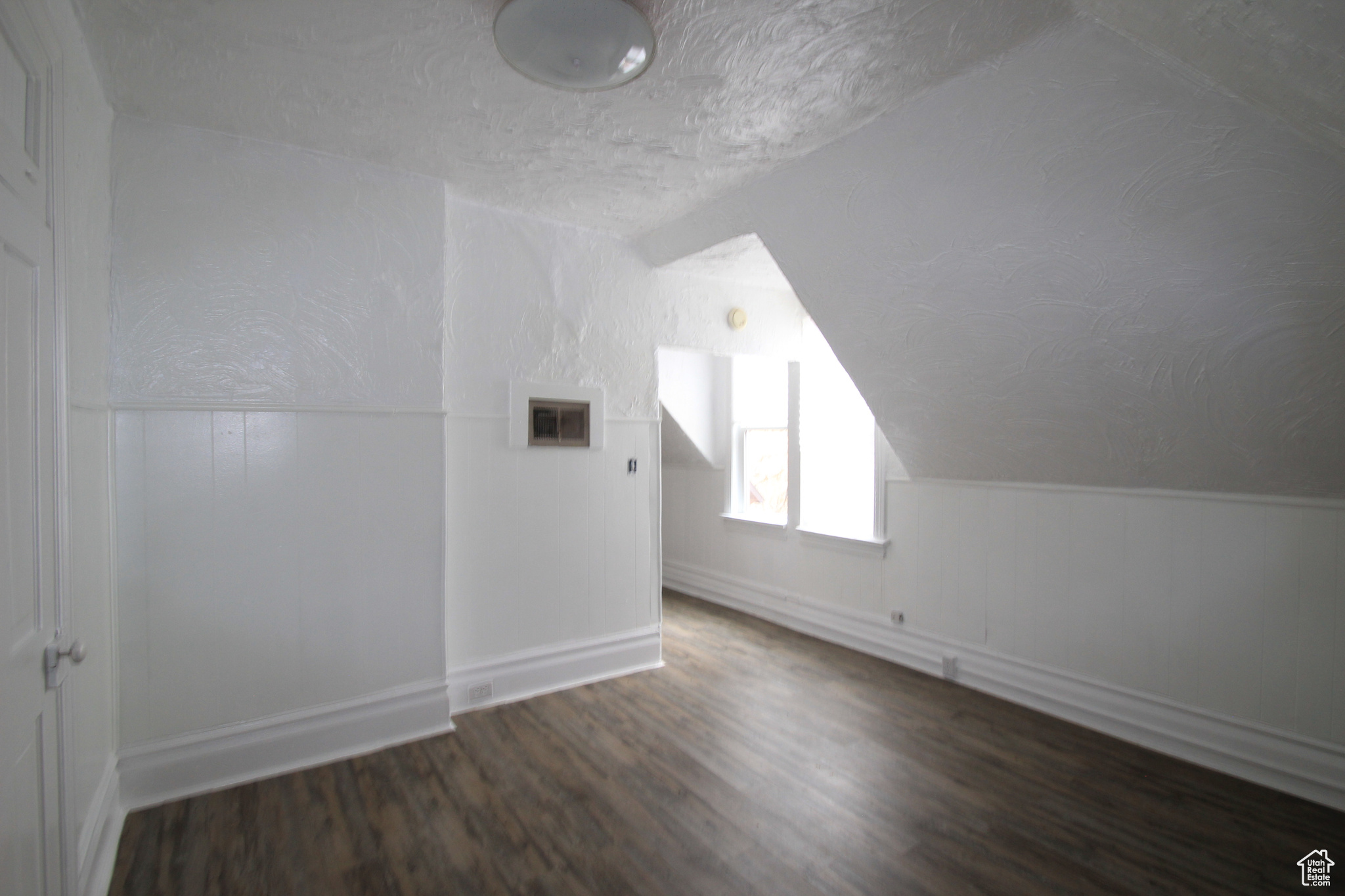 Bonus room featuring lofted ceiling, dark hardwood / wood-style floors, and a textured ceiling