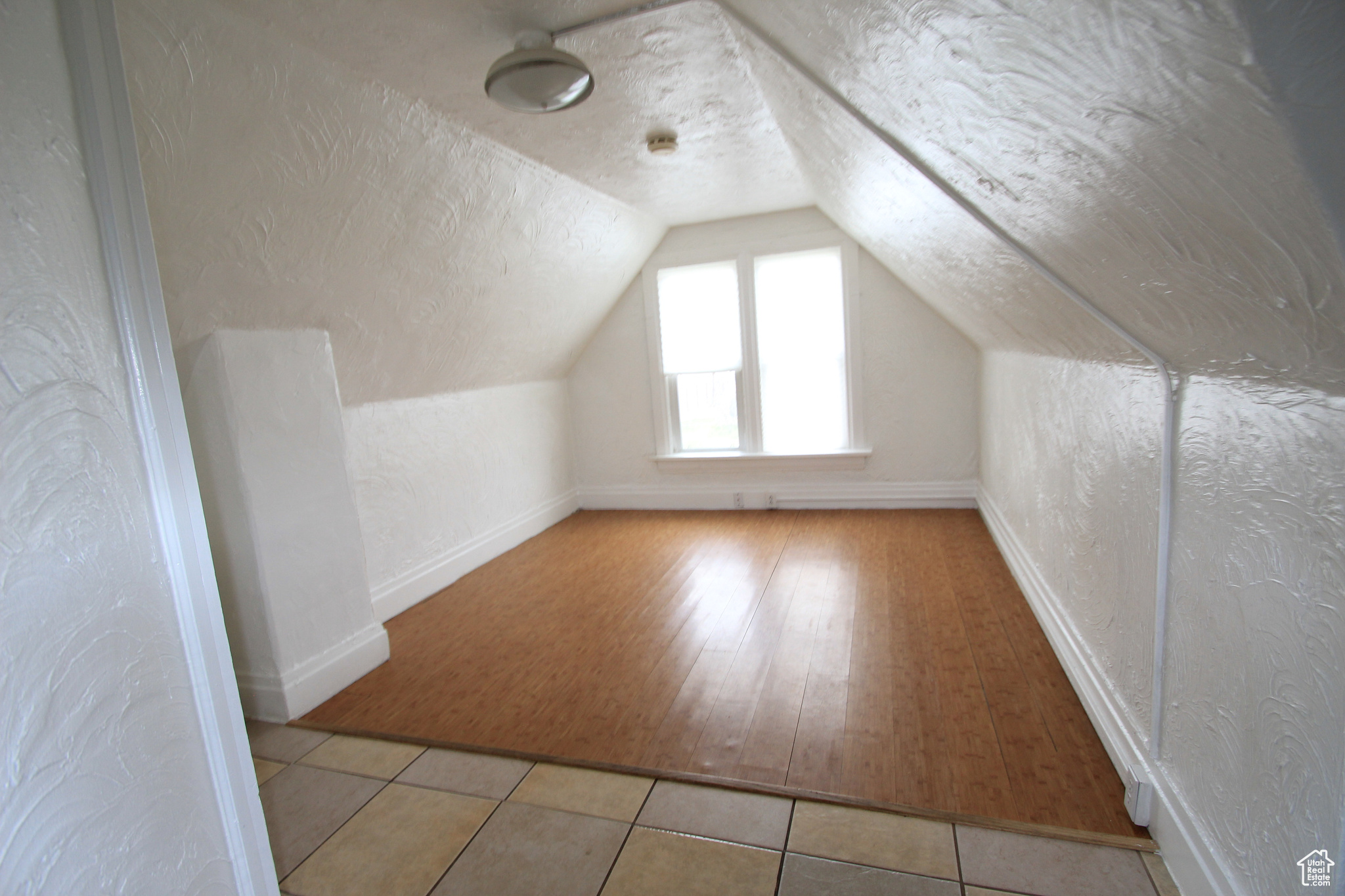 Bonus room with vaulted ceiling and light wood-type flooring