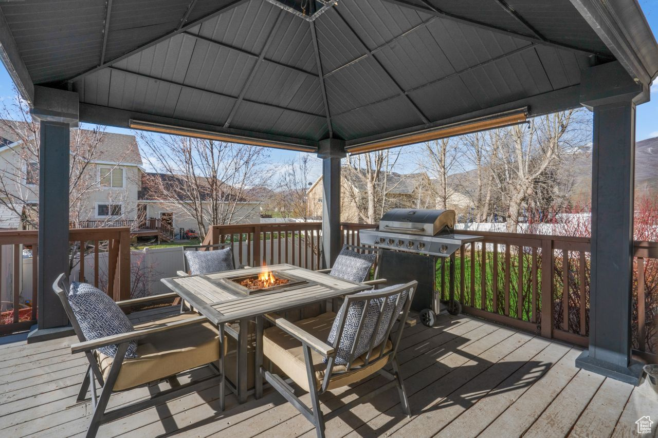 Wooden deck featuring a grill, a gazebo, and an outdoor fire pit