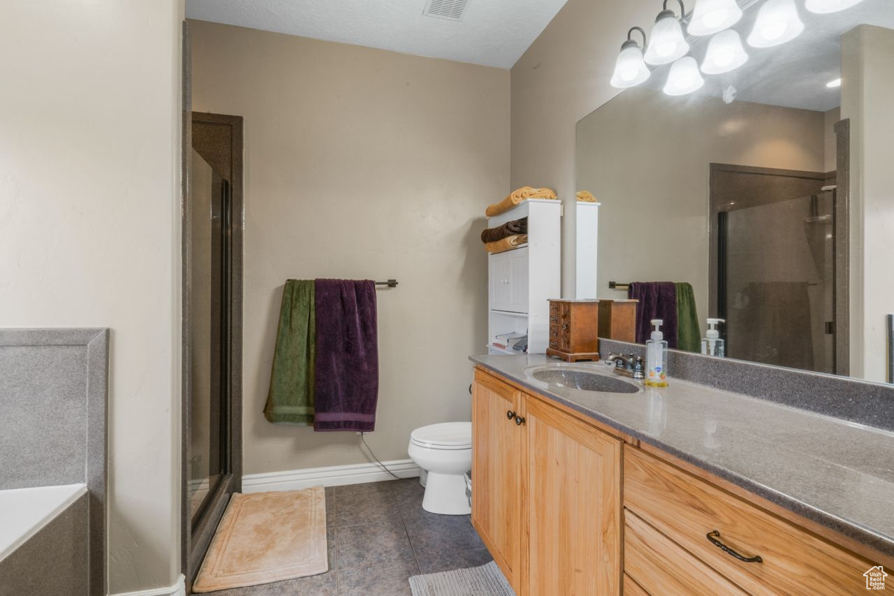 Full bathroom with vanity, tile floors, toilet, and shower with separate bathtub