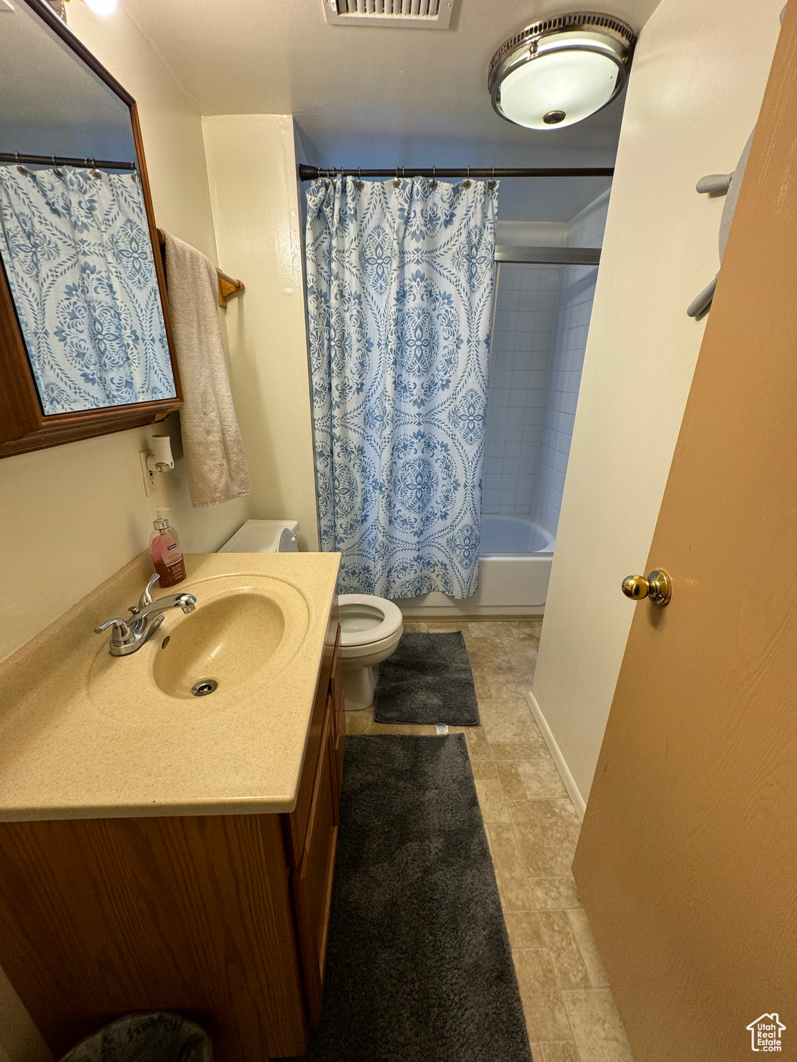 Full bathroom with oversized vanity, shower / bath combination with curtain, toilet, and tile flooring