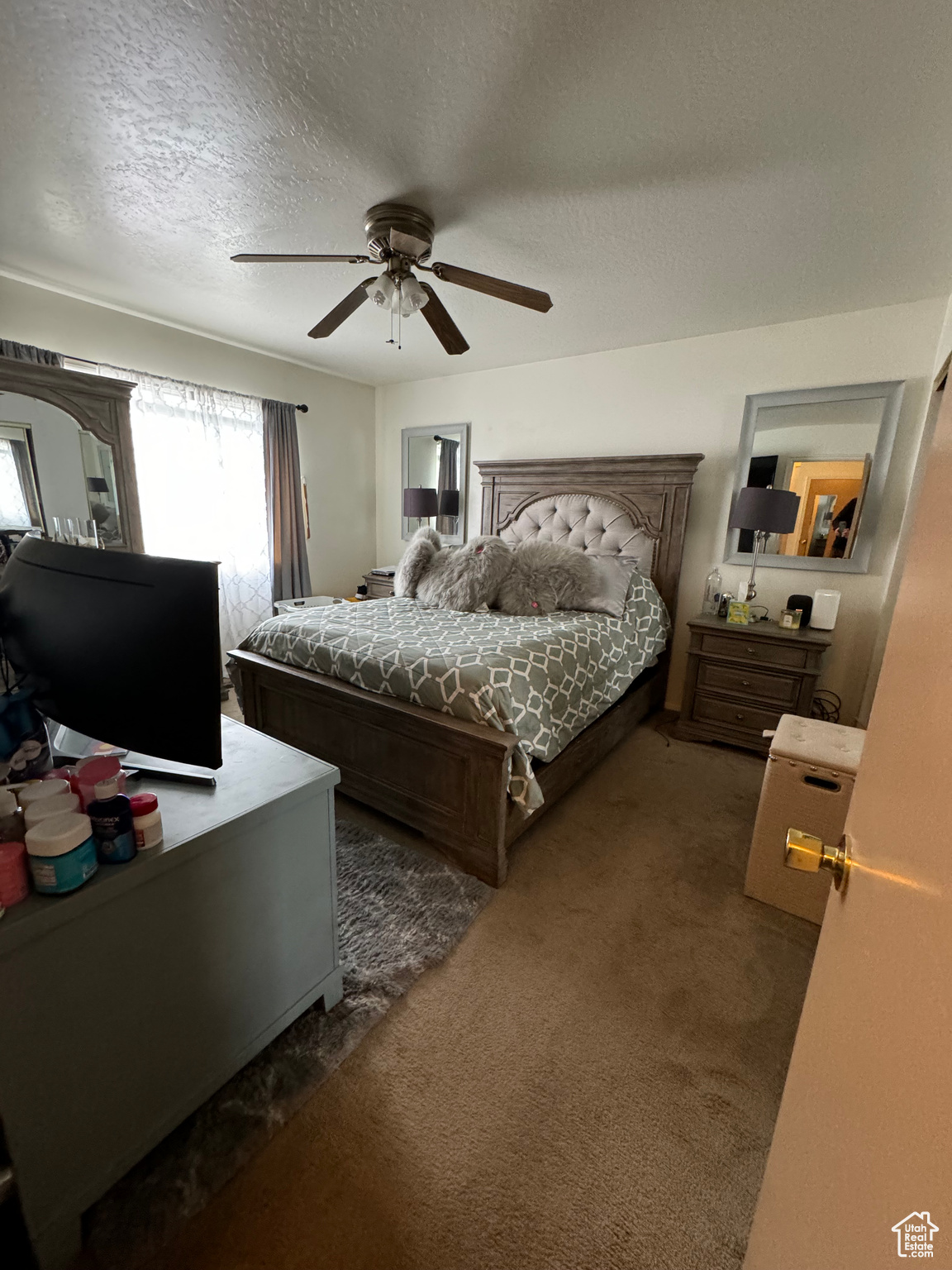 Bedroom with ceiling fan, dark carpet, and a textured ceiling