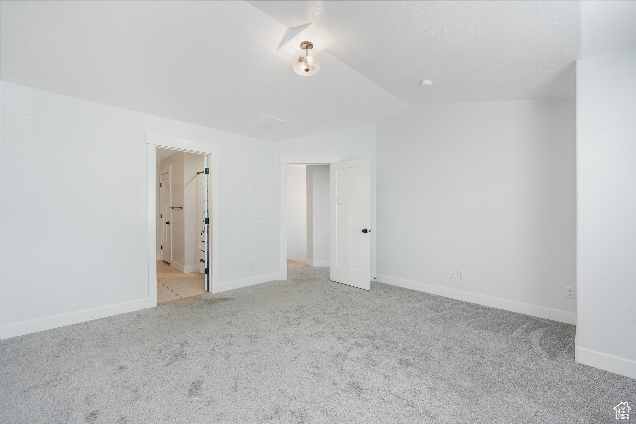 Unfurnished bedroom with light colored carpet and lofted ceiling