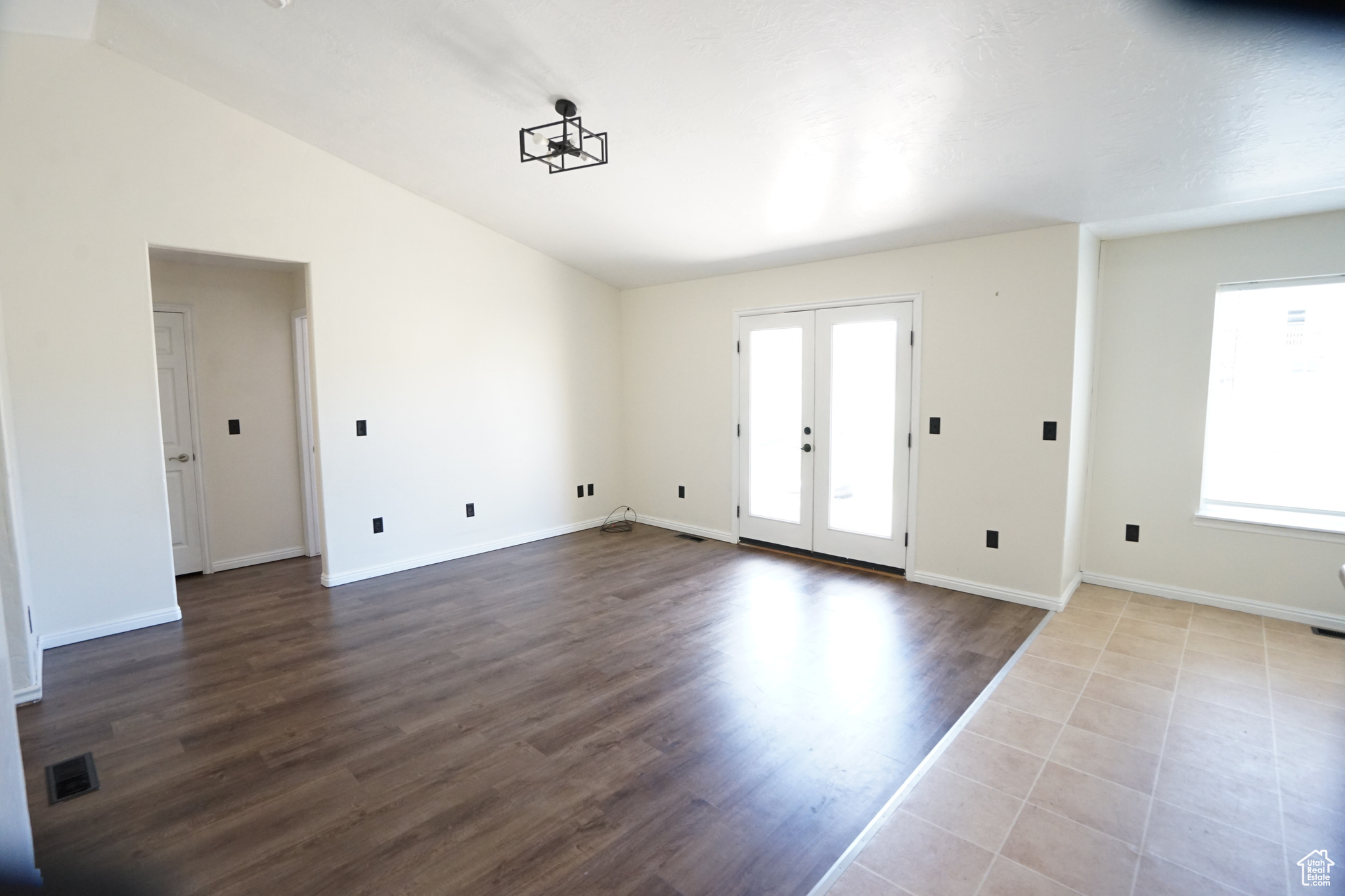 Empty room with lofted ceiling, french doors, and light tile flooring
