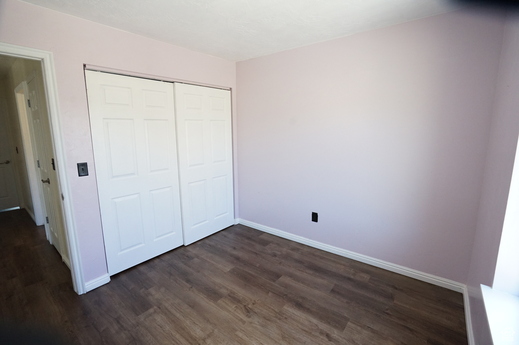Unfurnished bedroom with dark wood-type flooring and a closet
