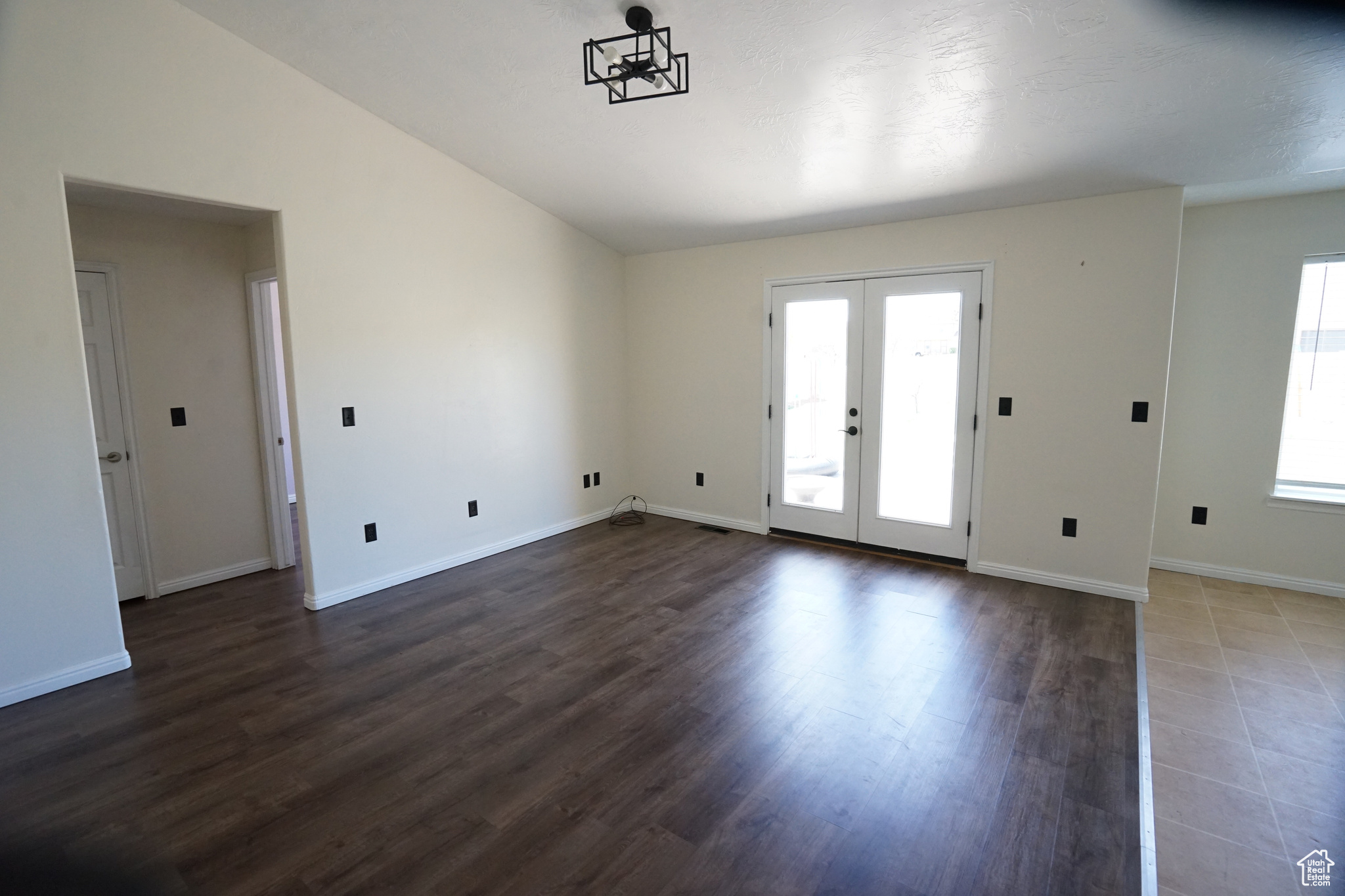 Unfurnished room featuring lofted ceiling, french doors, and dark tile flooring