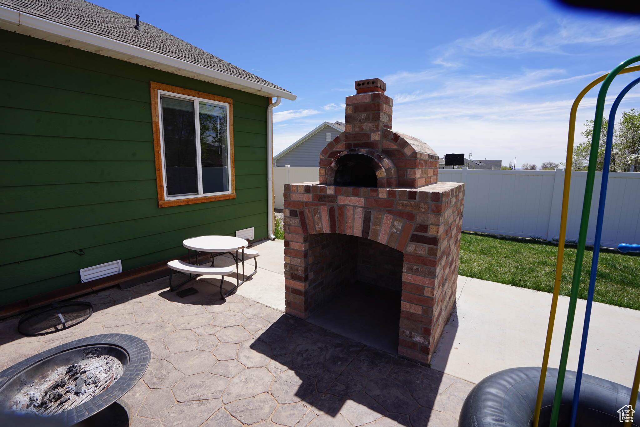 View of patio featuring a fire pit and an outdoor brick fireplace