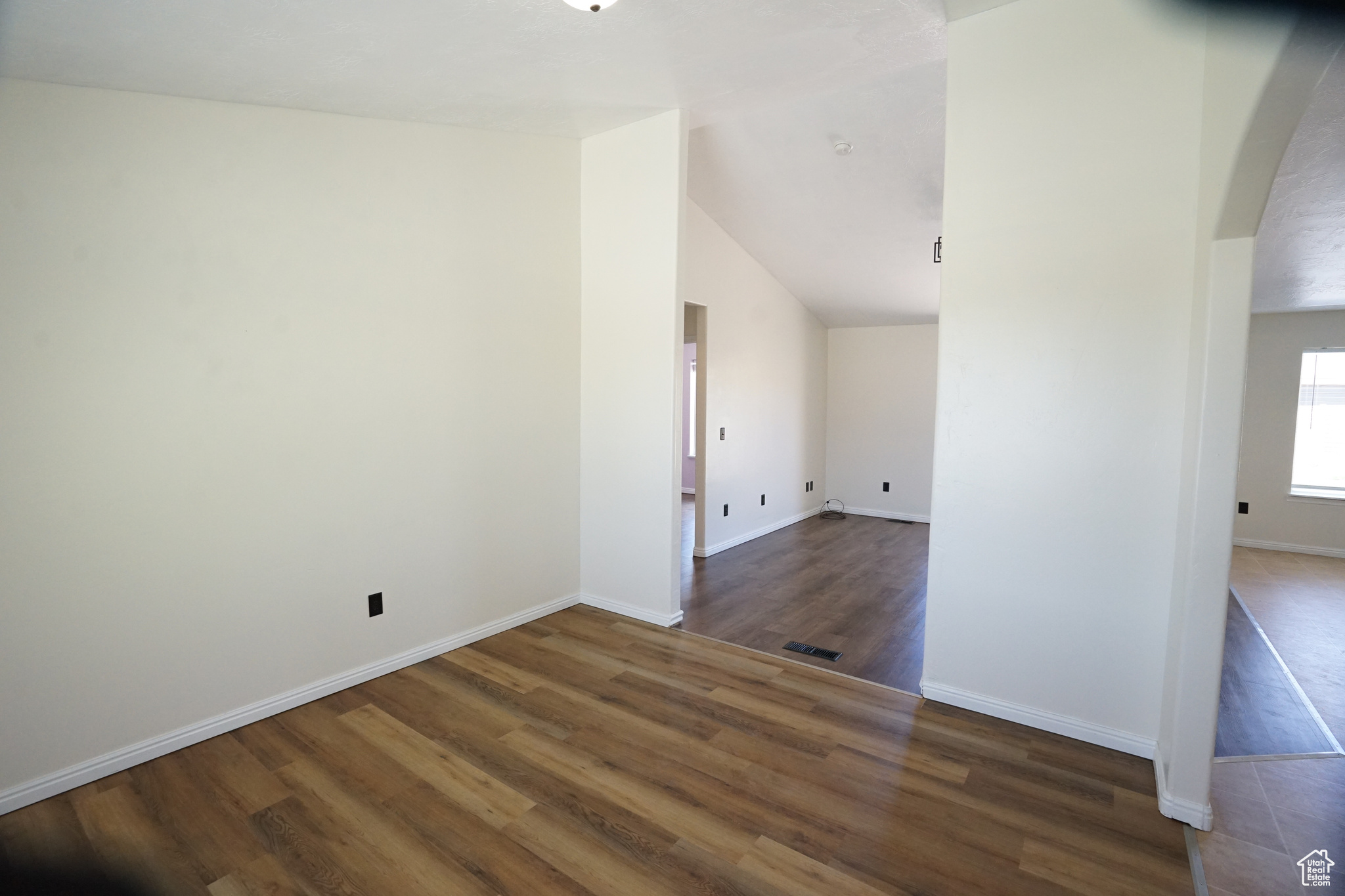 Spare room featuring vaulted ceiling and dark hardwood / wood-style flooring