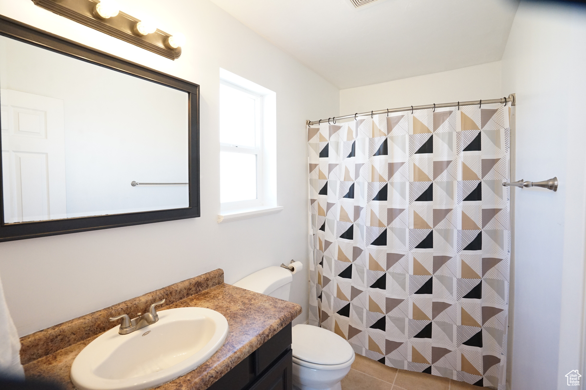Bathroom featuring vanity with extensive cabinet space, toilet, and tile floors