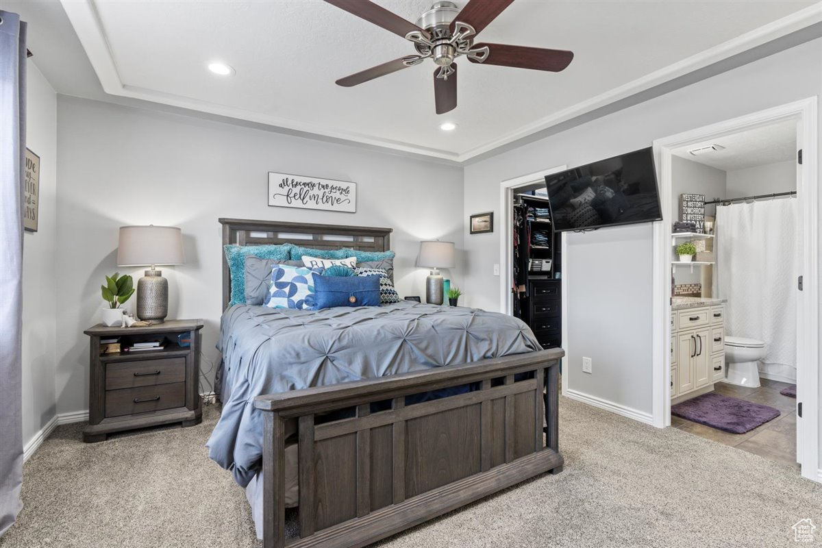 Bedroom featuring light colored carpet, ensuite bath, and ceiling fan
