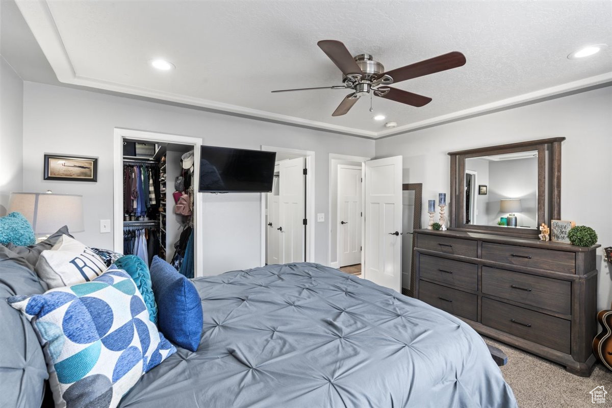 Bedroom featuring a spacious closet, ceiling fan, light carpet, and a closet
