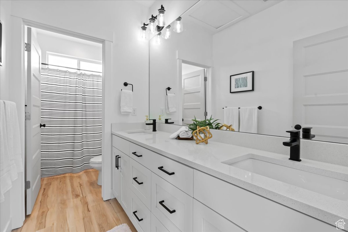 Bathroom featuring hardwood / wood-style floors, toilet, and double sink vanity