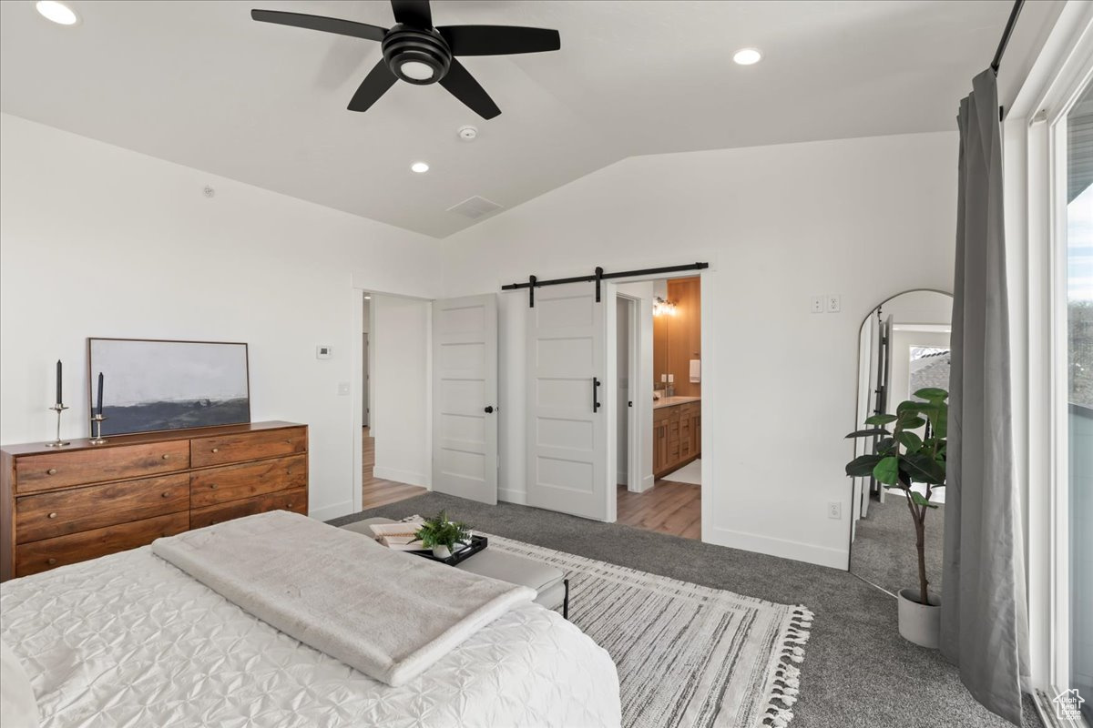 Bedroom featuring lofted ceiling, dark colored carpet, ceiling fan, and a barn door