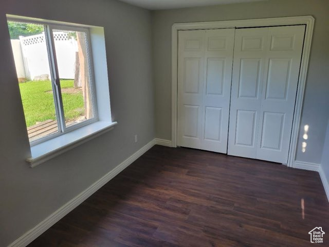 Unfurnished bedroom with a closet and dark wood-type flooring