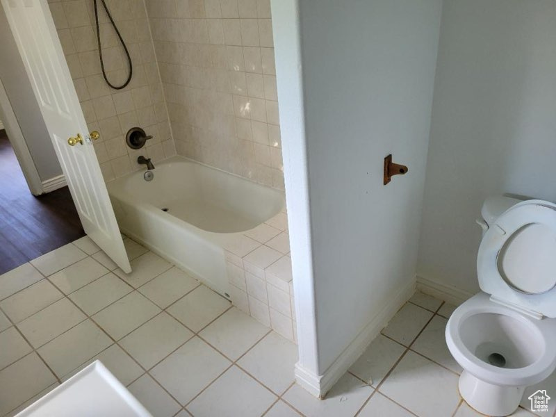 Bathroom with wood-type flooring, tiled shower / bath combo, and toilet