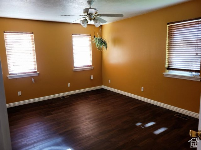 Empty room featuring ceiling fan and dark wood-type flooring