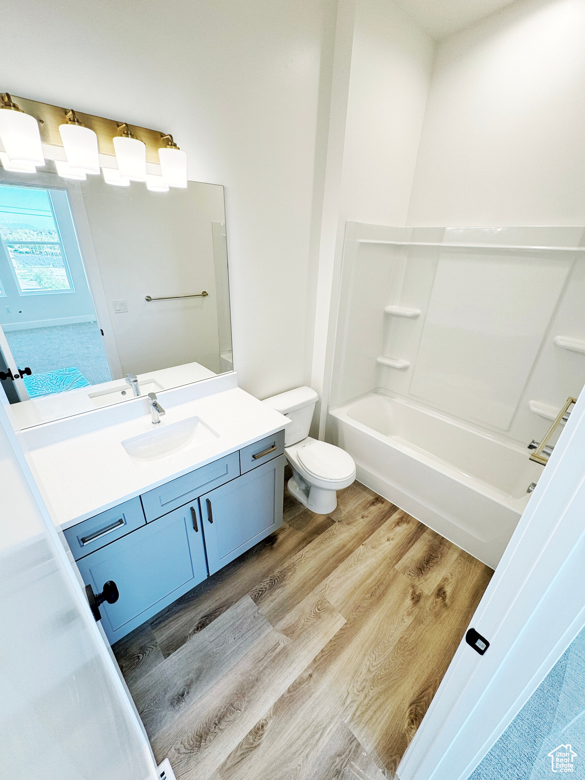 Full bathroom with LVP flooring, vanity, toilet, and shower / tub combination