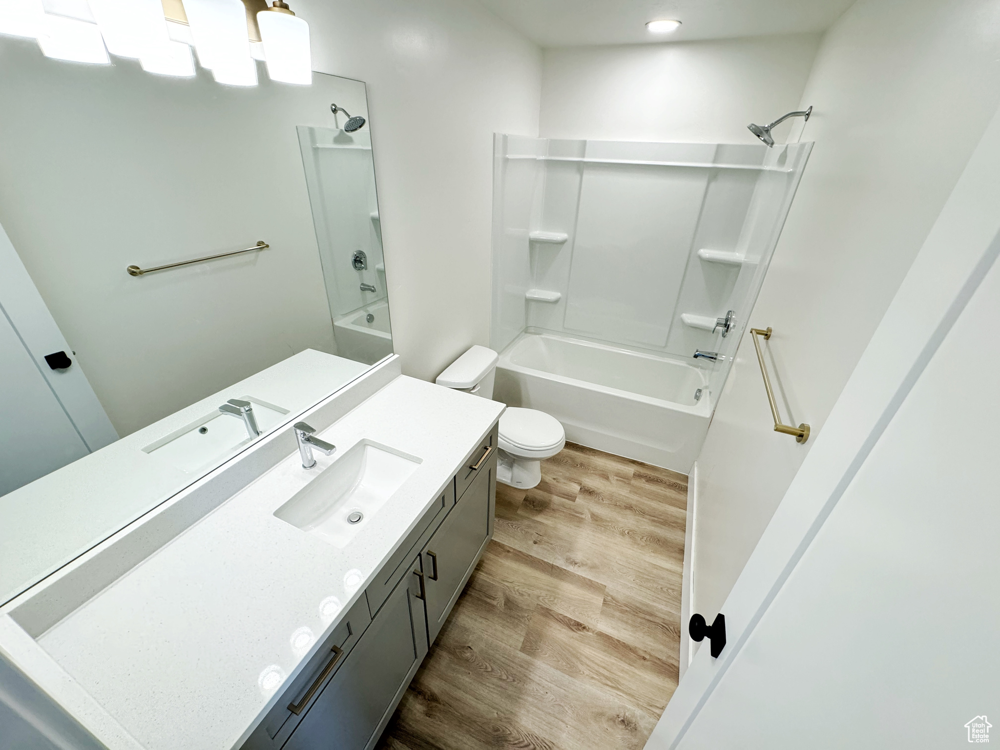 Full bathroom with LVP flooring, oversized vanity, toilet, and  shower combination
