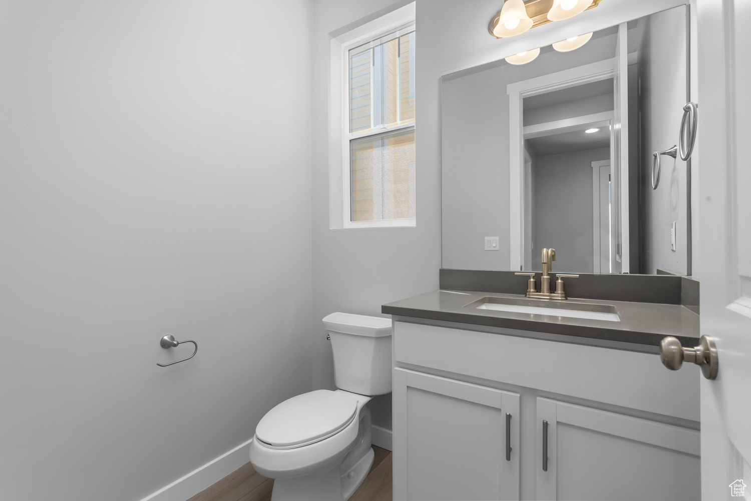 Bathroom featuring a wealth of natural light, oversized vanity, toilet, and hardwood / wood-style floors