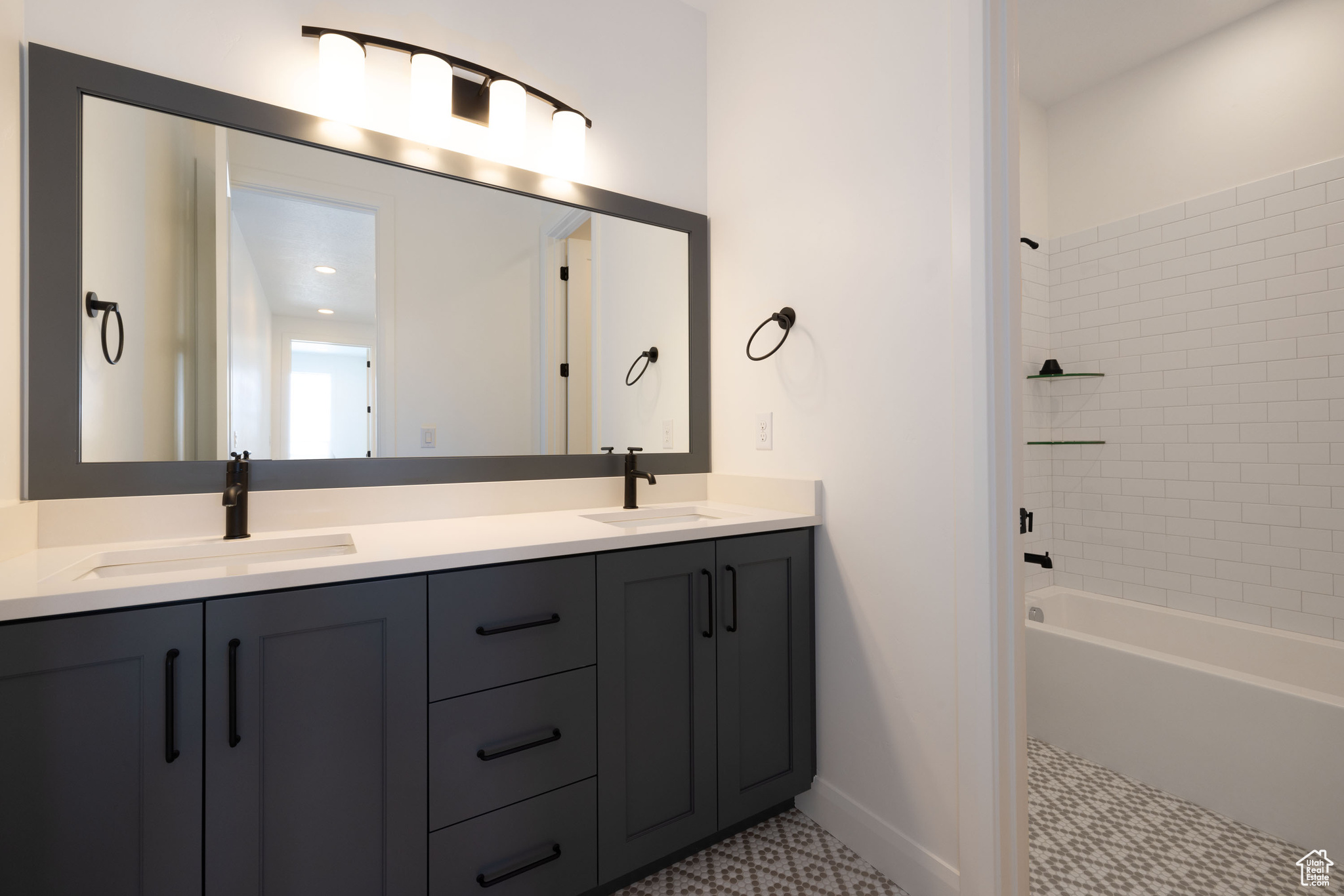 Bathroom featuring tiled shower / bath, tile patterned floors, and dual vanity