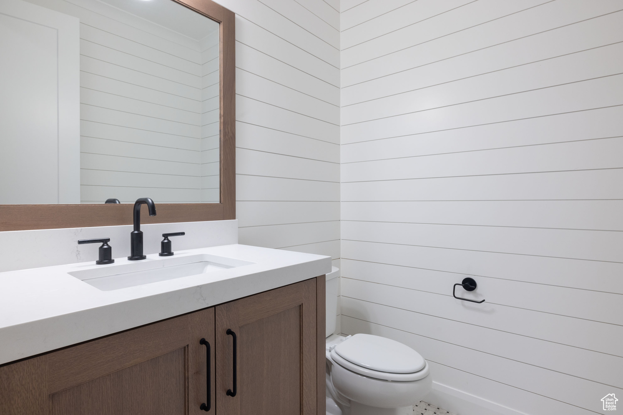 Bathroom with vanity, wood walls, and toilet