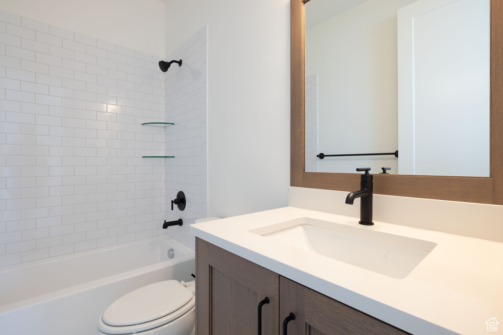 Full bathroom featuring vanity, tiled shower / bath combo, and toilet