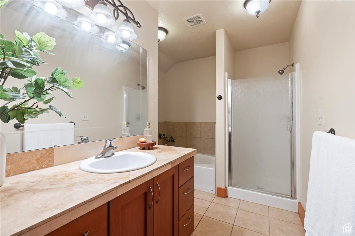 Bathroom with tub and separate walk-in shower, tile flooring, and large vanity