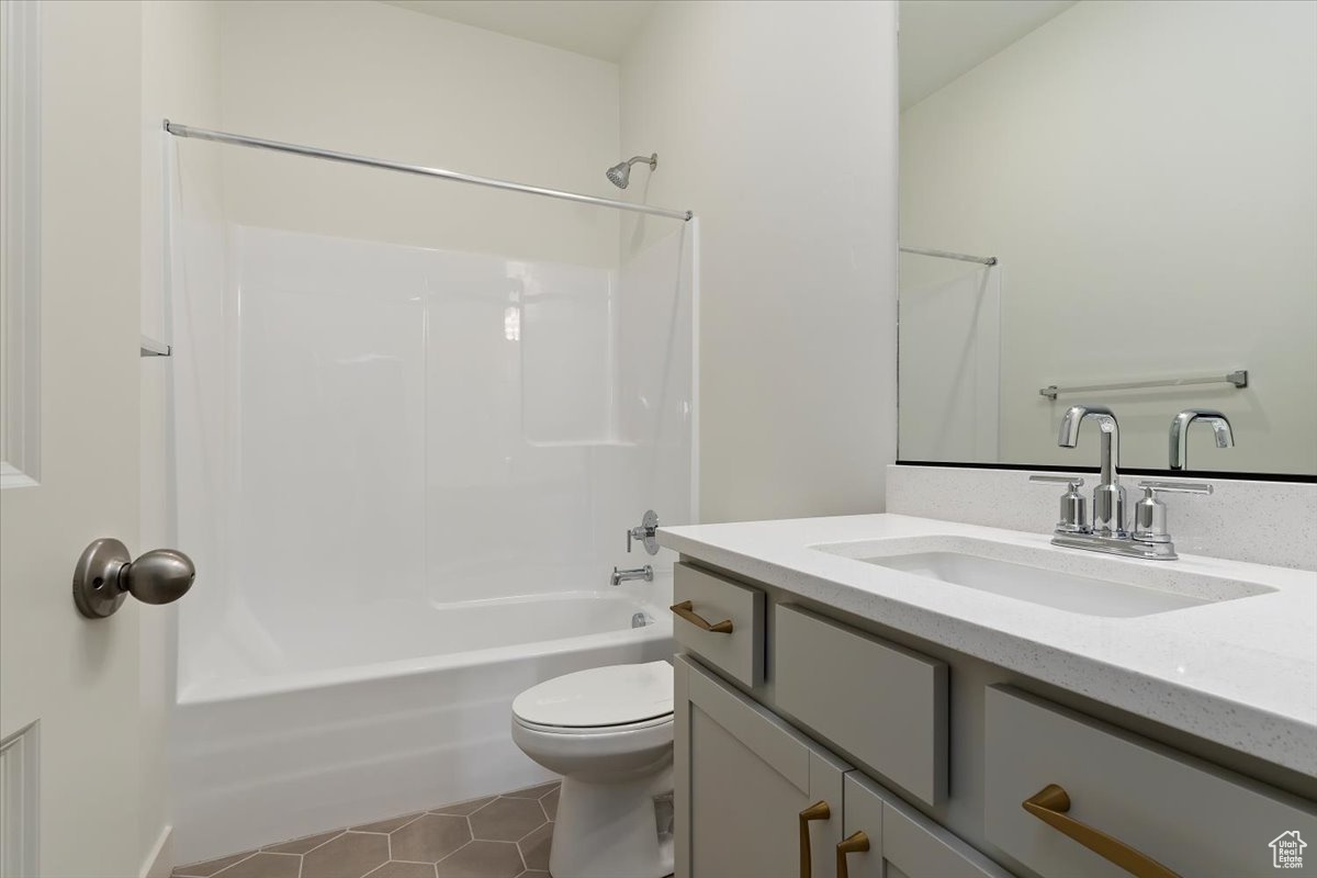 Full bathroom with tile flooring, oversized vanity, shower / washtub combination, and toilet