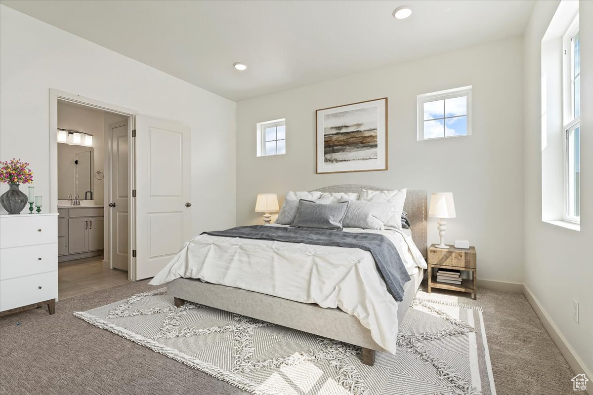 Bedroom with light carpet and connected bathroom